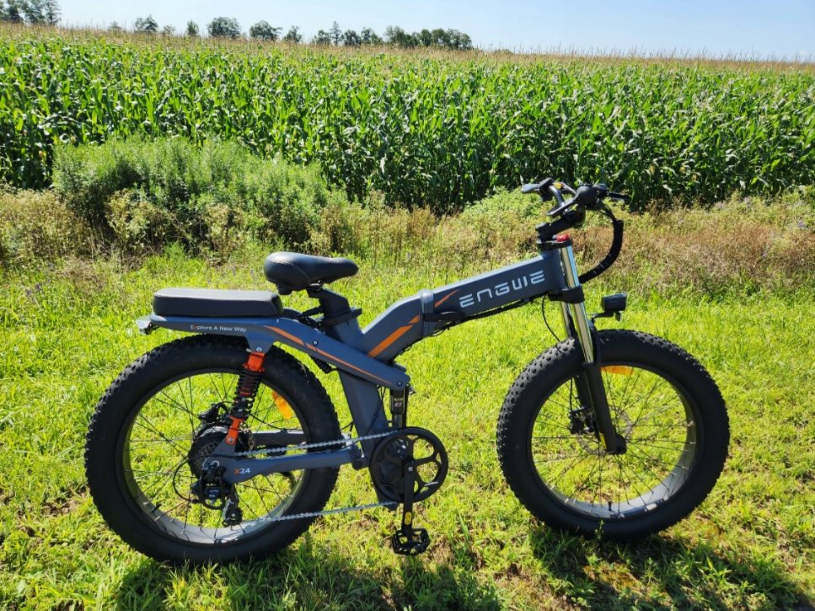 Una e-bike Engwe su un campo erboso vicino a un campo di mais.