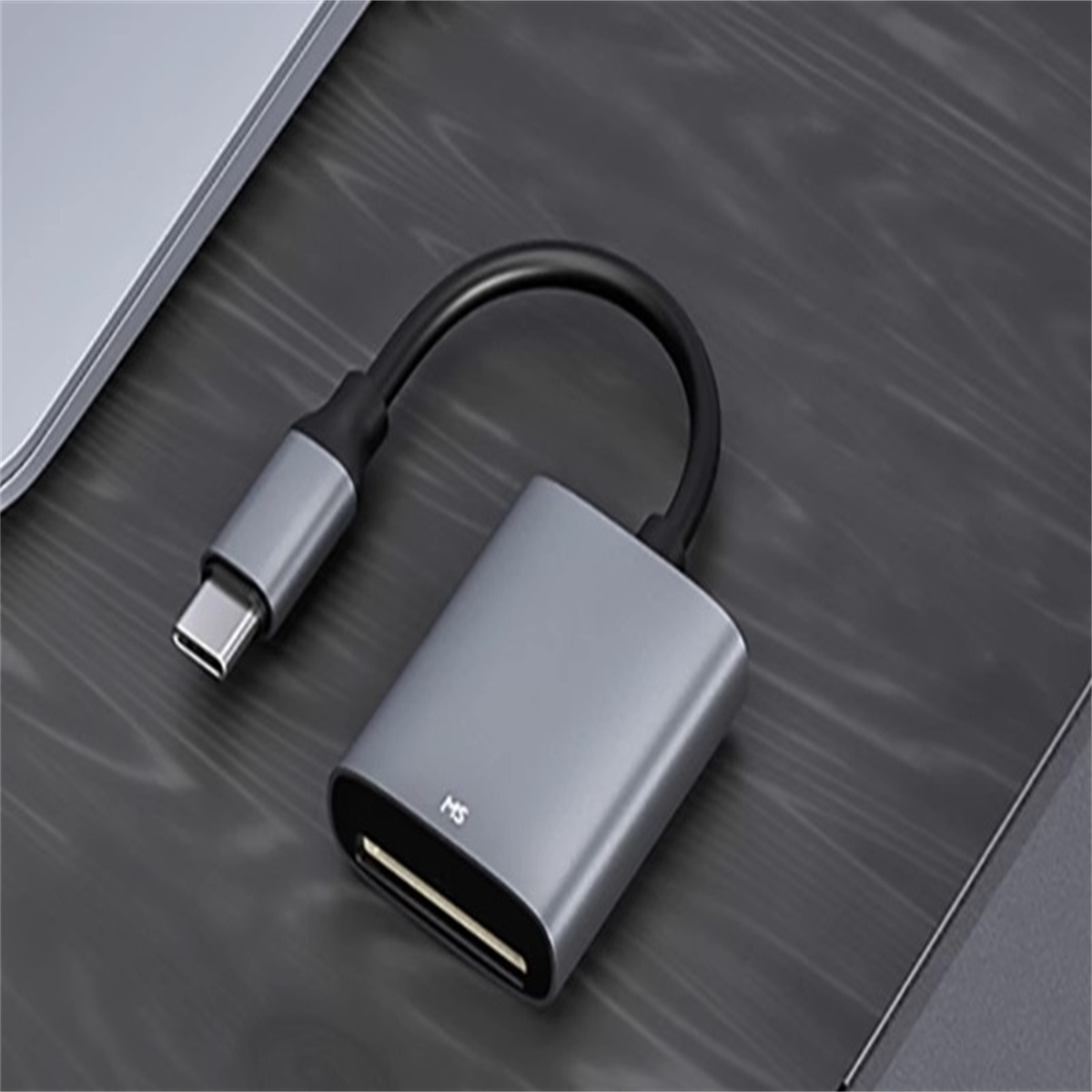 Ein grauer USB-C-Adapter, der mit einem grauen Kartenleser auf einer Holzoberfläche verbunden ist.