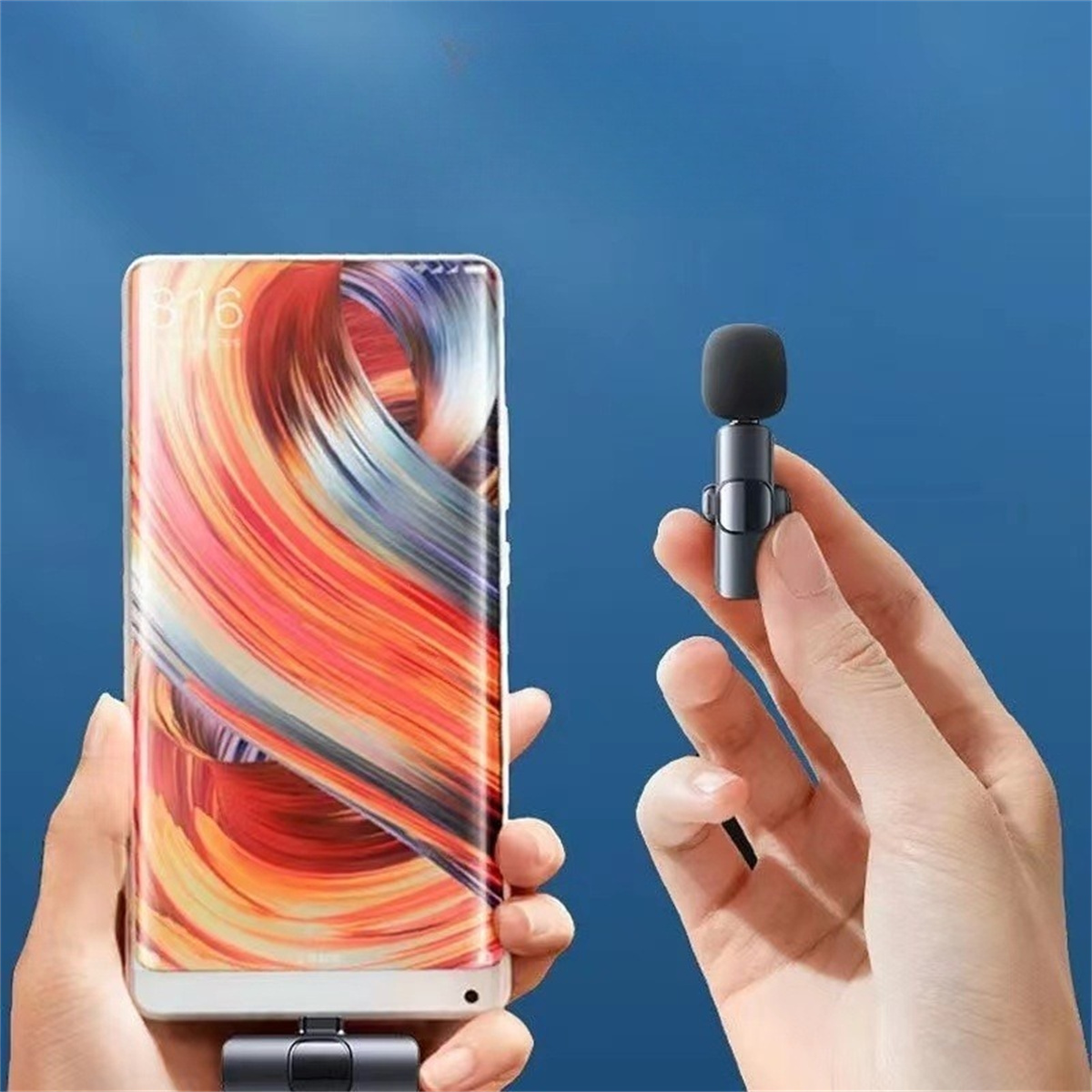 Ein kleines Mikrofon neben einem Telefon. Hände halten beides. Blauer und oranger Hintergrund.