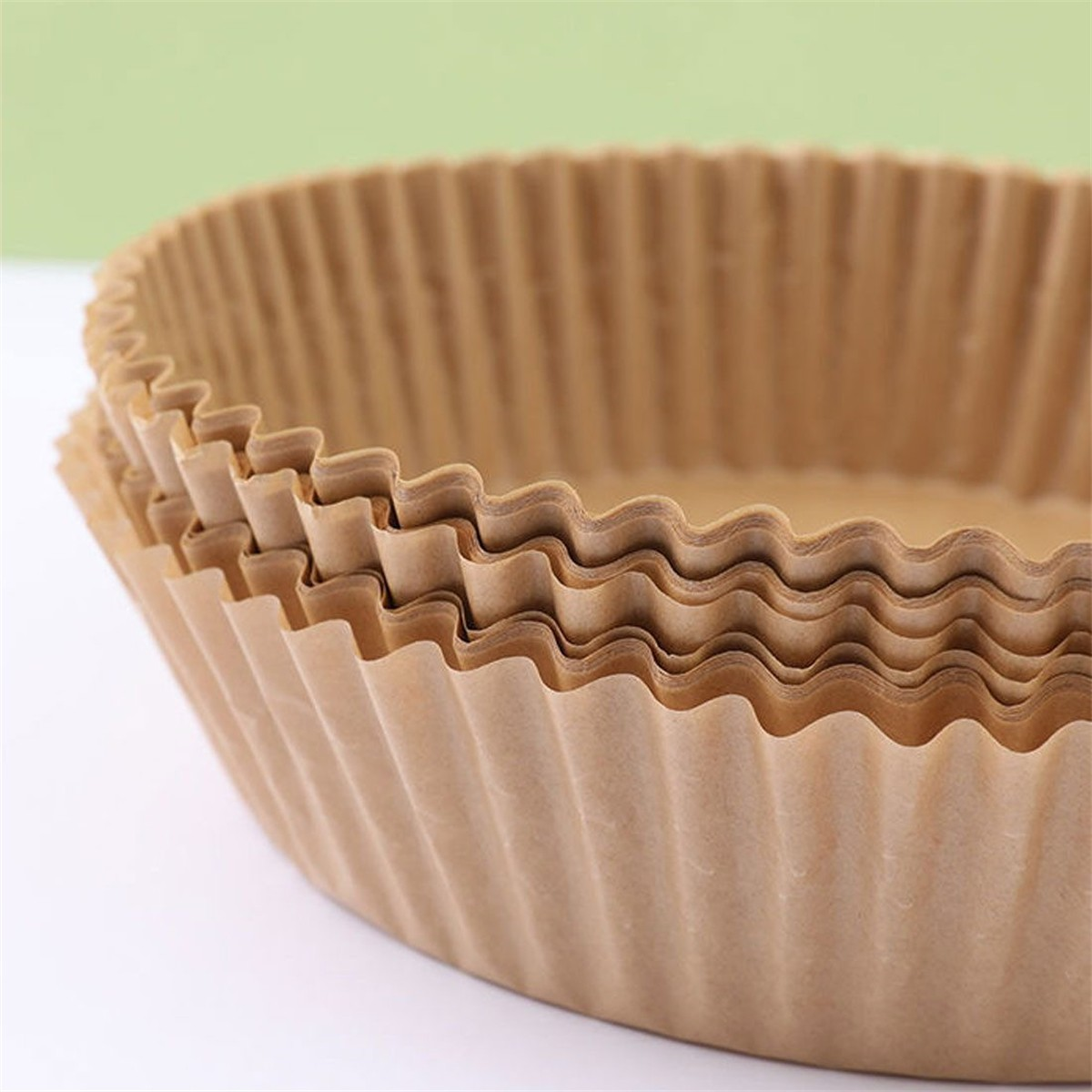 Stapel brauner, gewellter Papier-Frittierpapier-Einlagen auf weißem Grund.