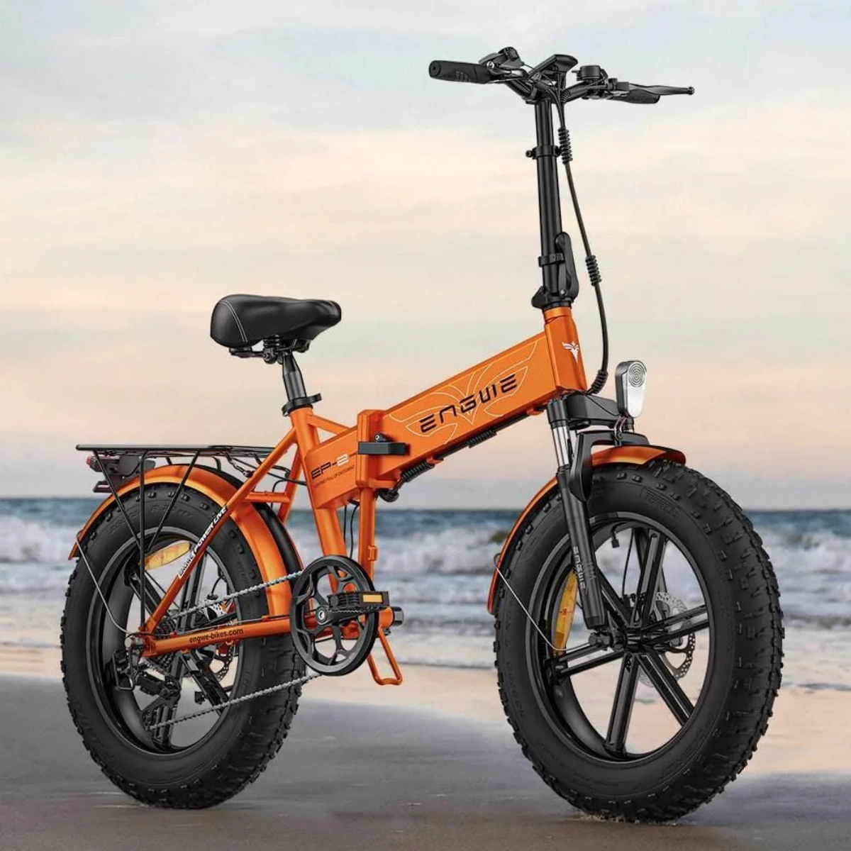 E-bike arancione su una spiaggia. Il mare è sullo sfondo.