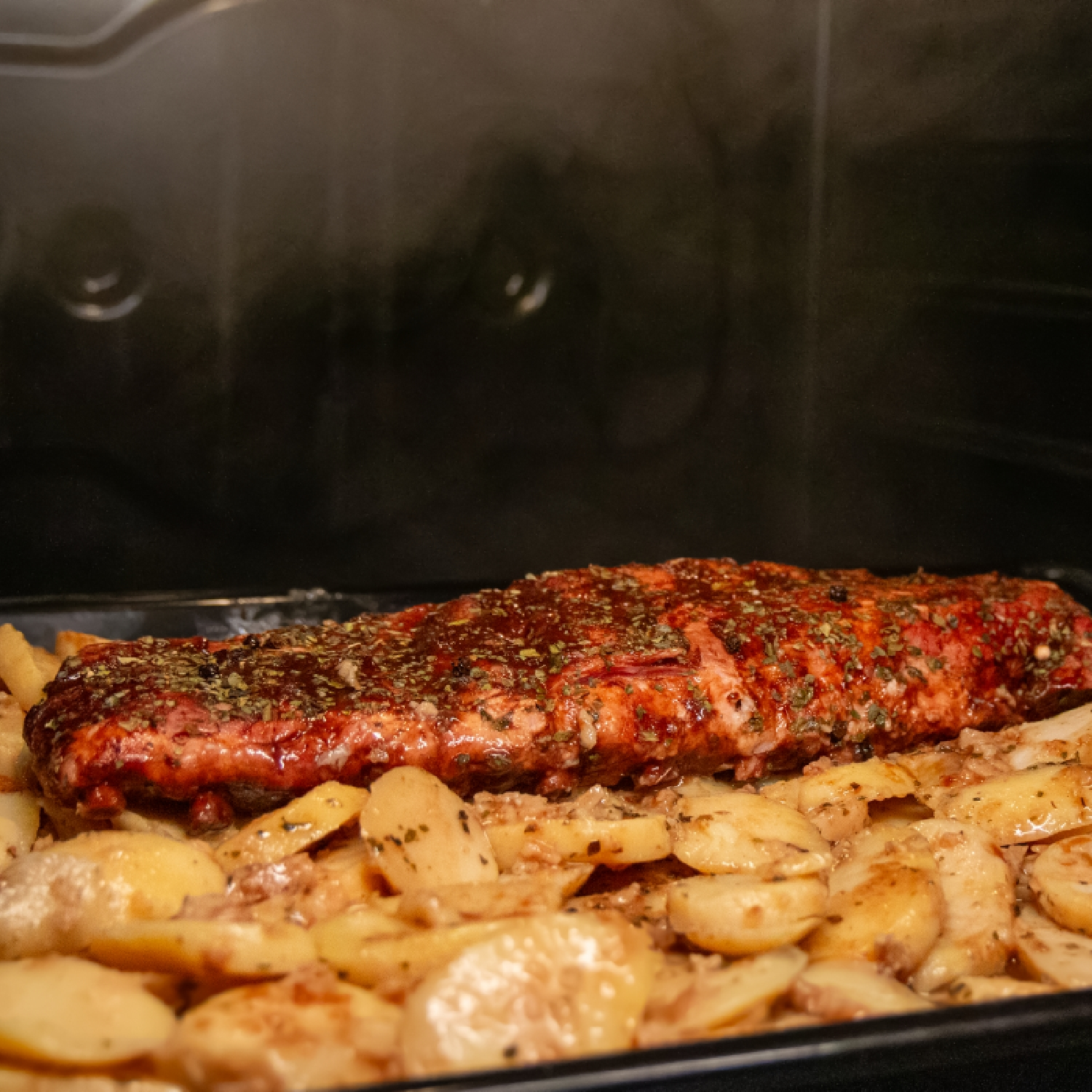 Gebratenes Fleisch mit Kartoffeln in einem Backblech, im Ofen.
