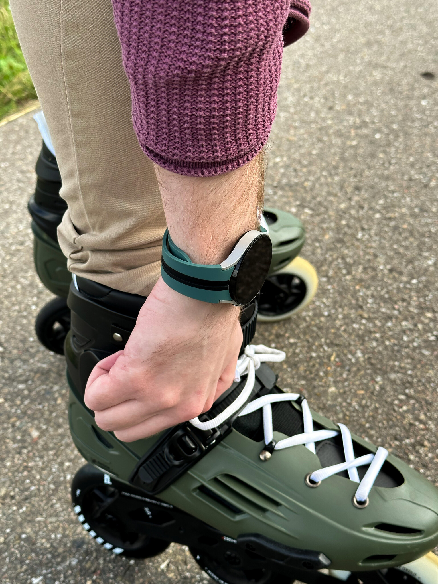 Person mit Rollschuhen und Smartwatch am Handgelenk. Grün und Schwarz sind sichtbar.