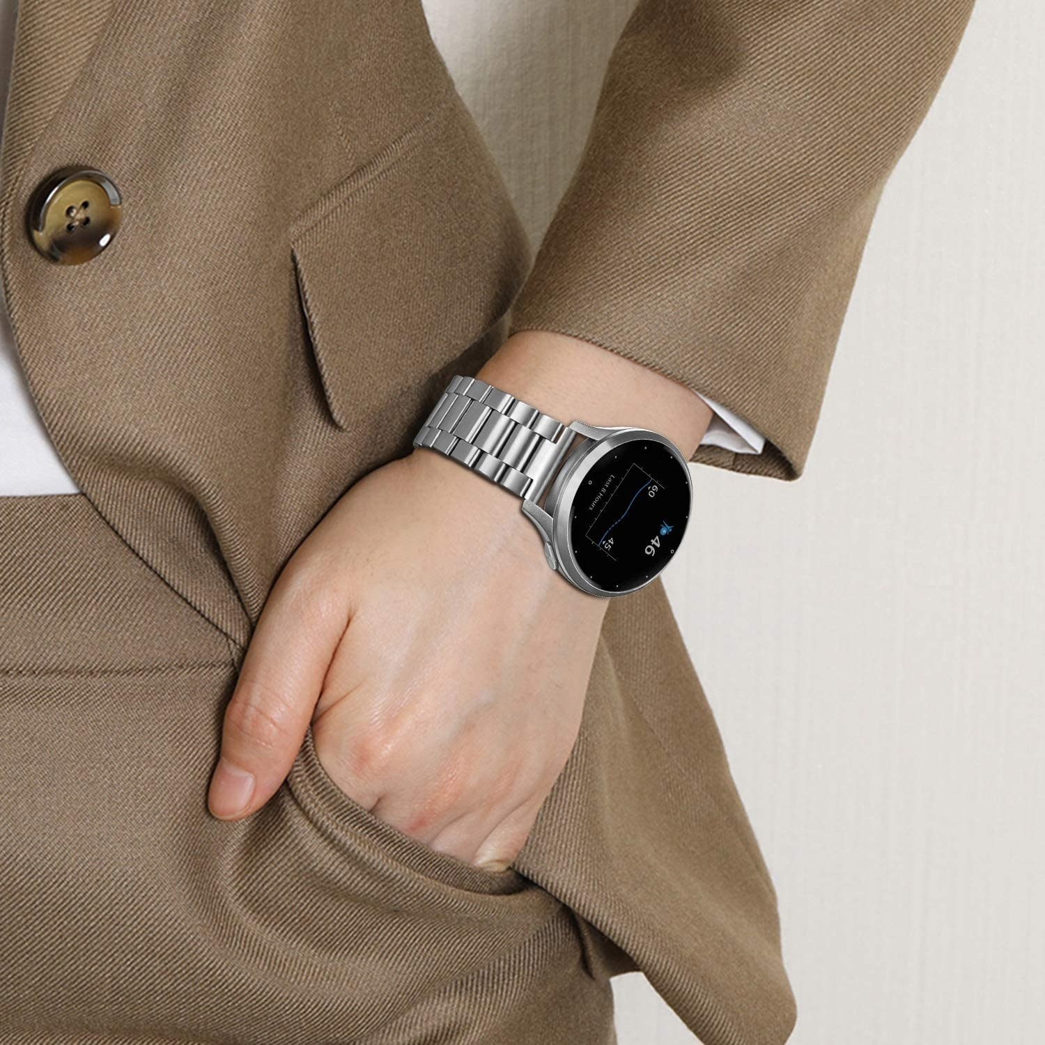 Eine Person im Anzug mit einer Uhr am Handgelenk. Die Uhr ist metallisch und hat einen schwarzen Bildschirm.