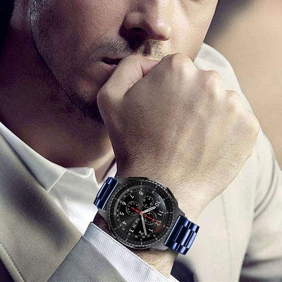 Ein Mann, der eine schwarze Smartwatch mit blauem Band trägt. Seine linke Hand ist zur Faust geballt.