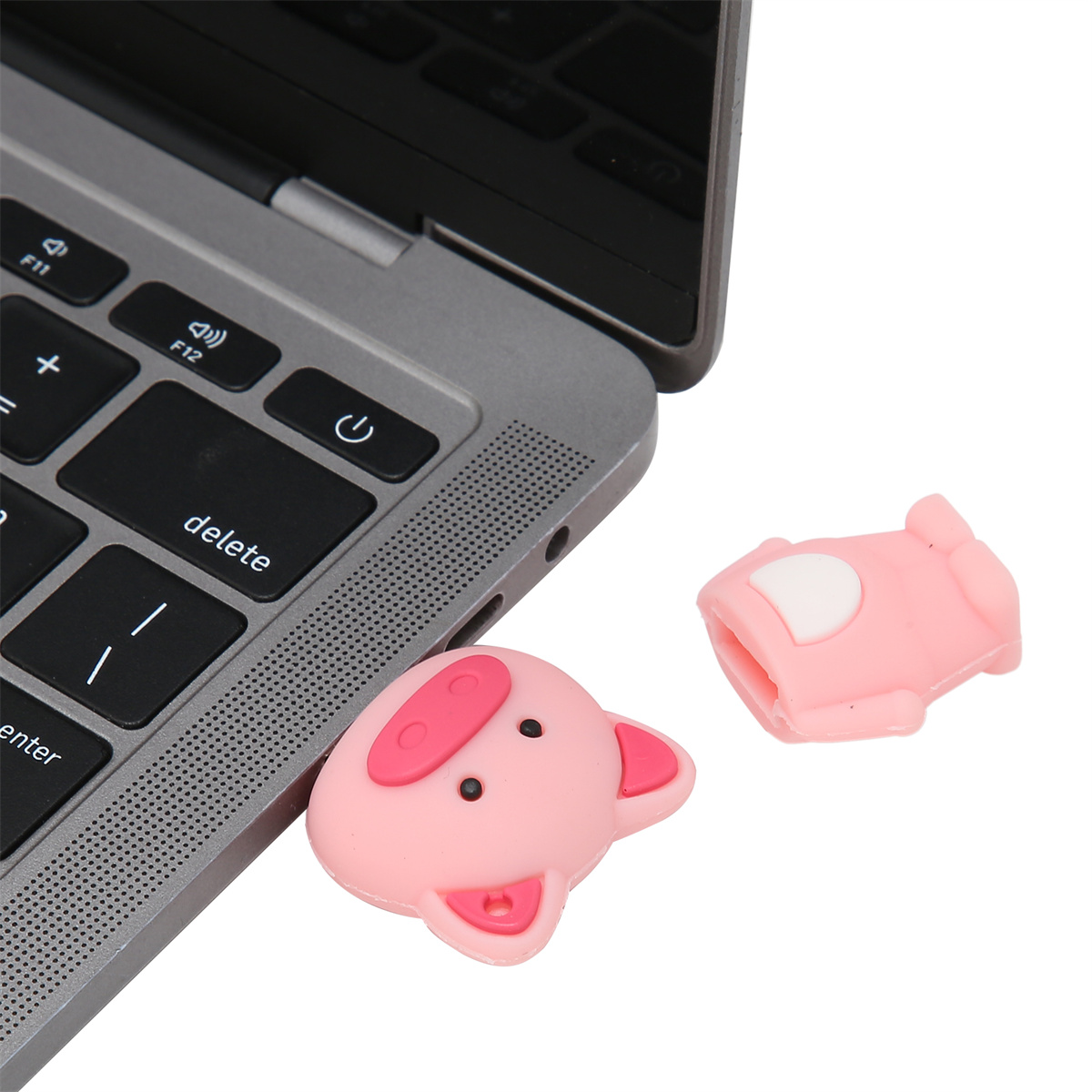 Nahaufnahme einer Laptop-Tastatur und zwei rosa schweineförmigen Anschluss-Schutzvorrichtungen.