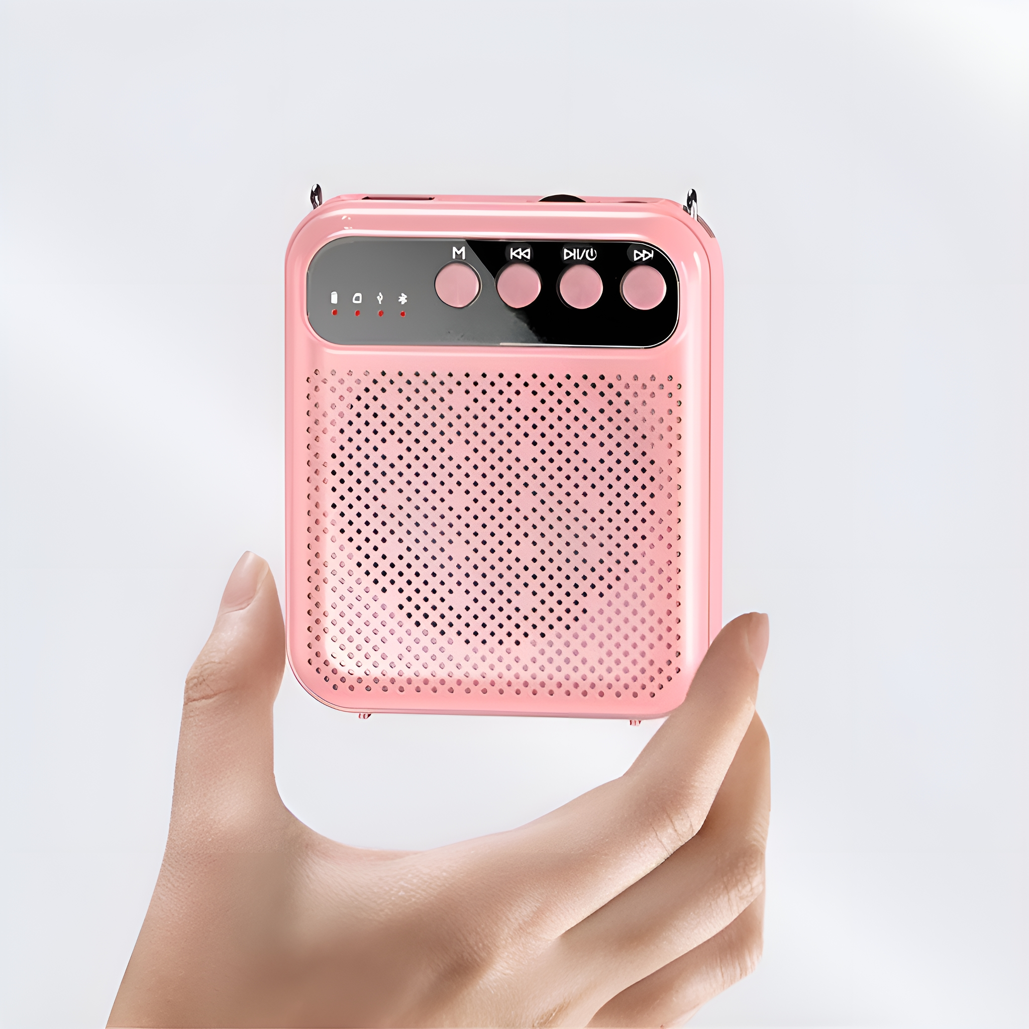 Ein pinkfarbener Lautsprecher wird in einer Hand gehalten. Es hat Knöpfe und ein Gitter.