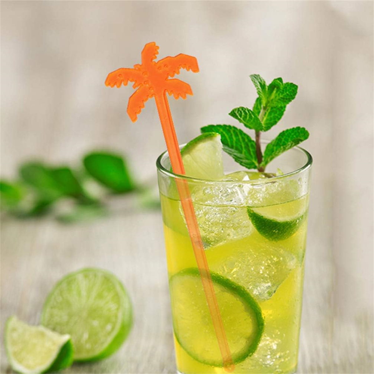 Ein Cocktail mit Palmen-Garnitur und Limettenscheiben. Minzblätter und Eis sind ebenfalls sichtbar.