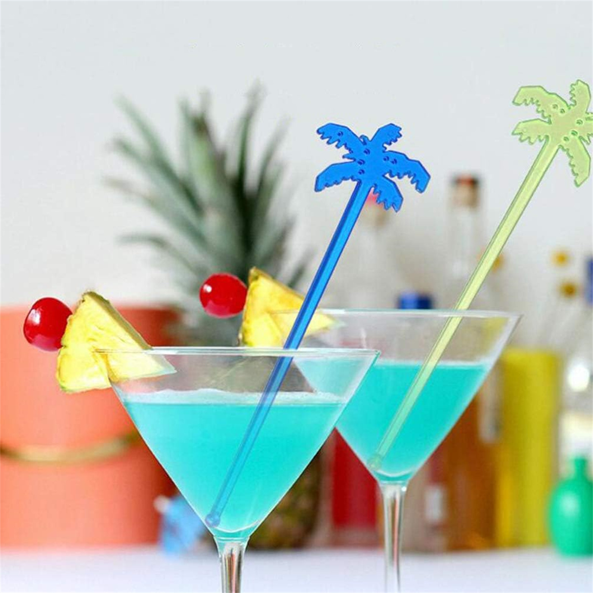 Zwei Cocktails mit blauer Flüssigkeit, Ananas und Palmen-Dekoration. Hell und tropisch.
