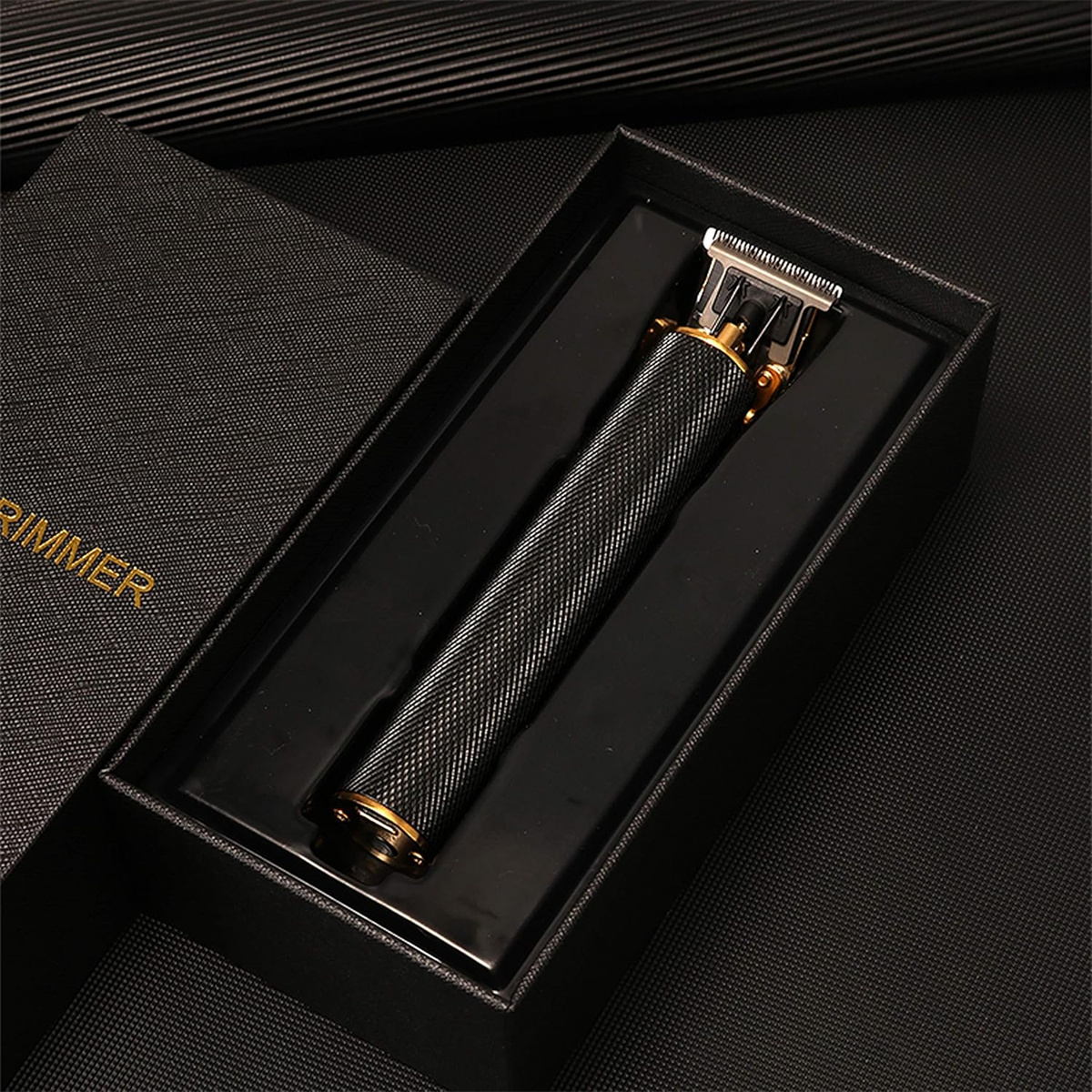 Schwarzer und goldener Trimmer in einer Box, mit strukturiertem Griff. Auf dunkler Oberfläche präsentiert.