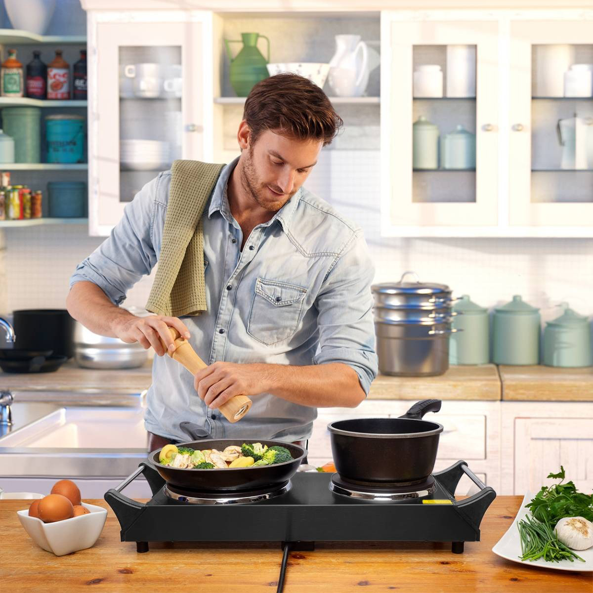 Man cooking. He is adding pepper to food in a pan on a stove.