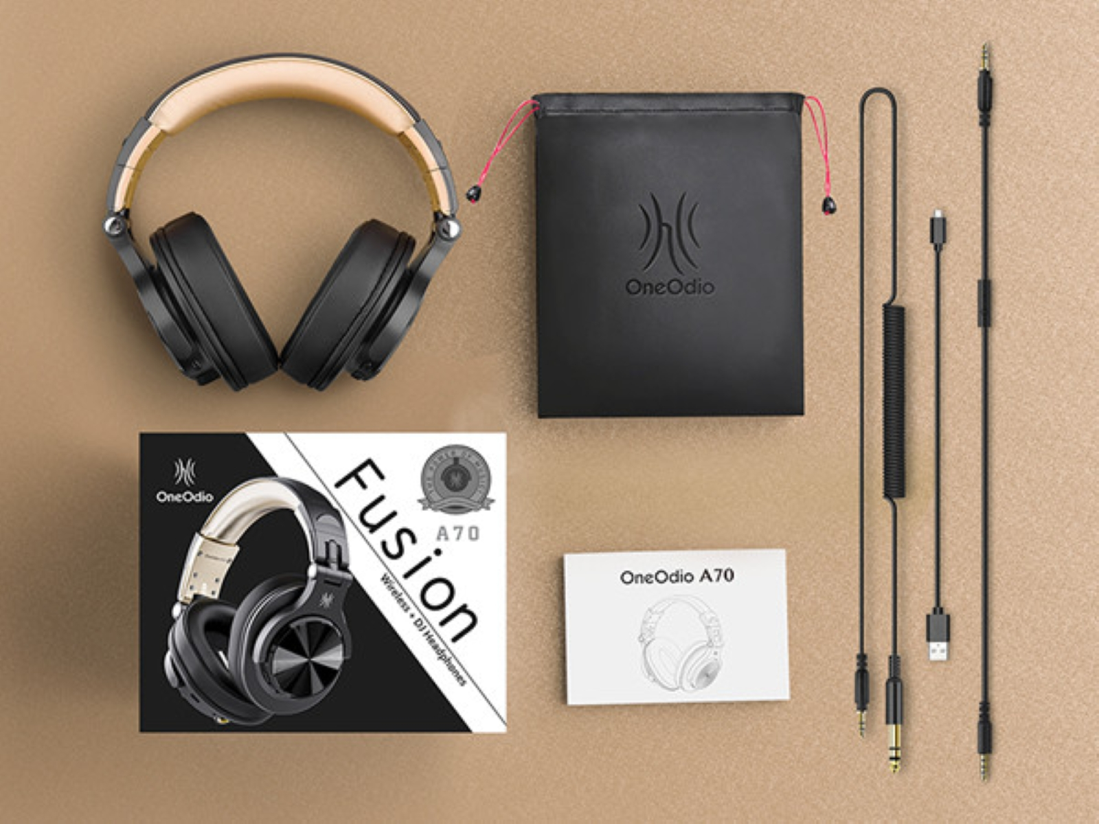 Headphones, case, cables, and box are on a tan surface. Headphones are black and tan, and the box says Fusion.