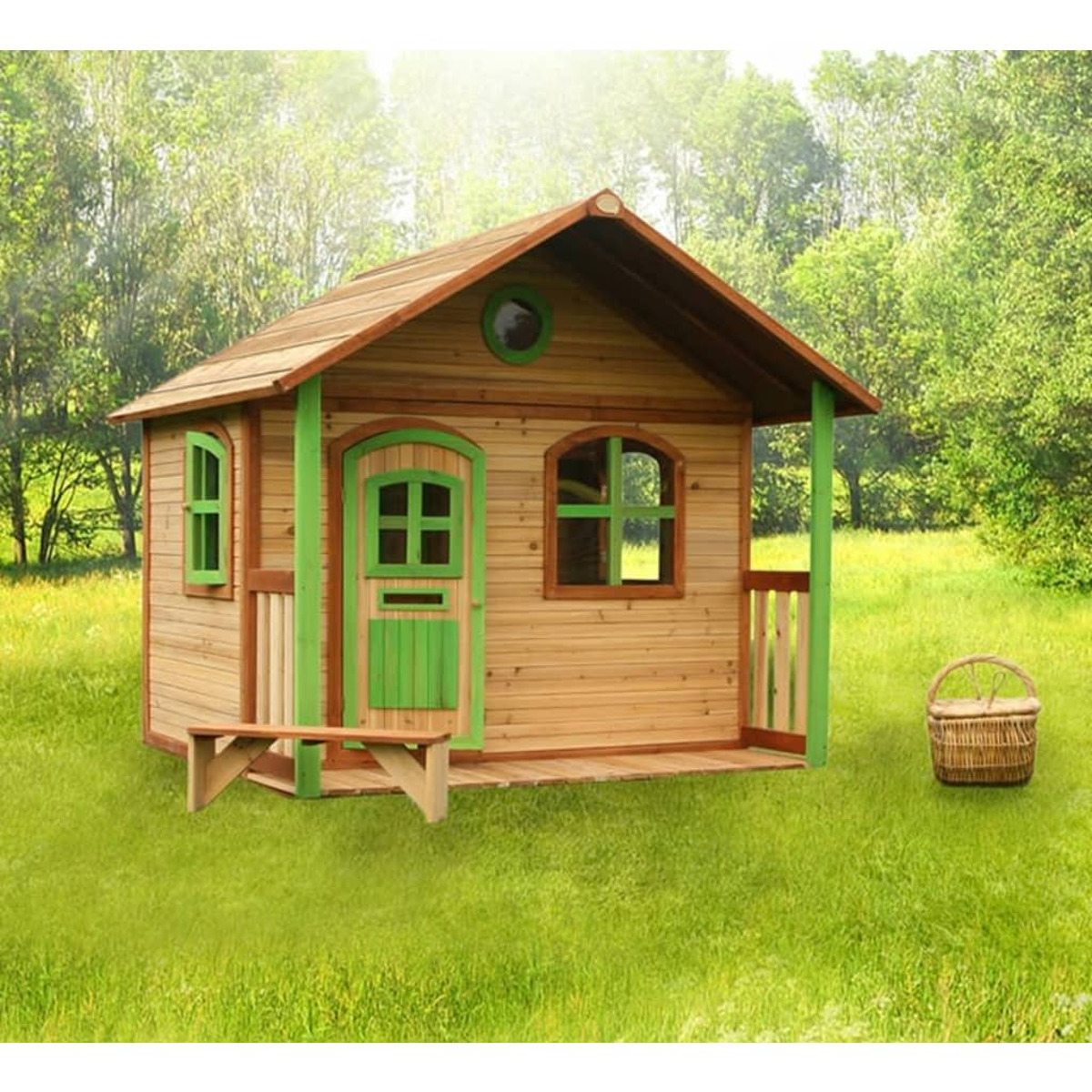Ein Holzspielhaus mit grüner Tür und Akzenten, auf einer Wiese mit Bäumen im Hintergrund.