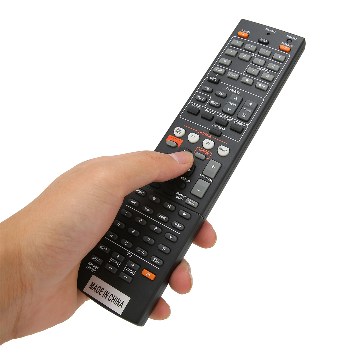 Hand, die eine schwarze Fernbedienung hält. Viele Knöpfe und orangefarbener Text. Weißer Hintergrund.