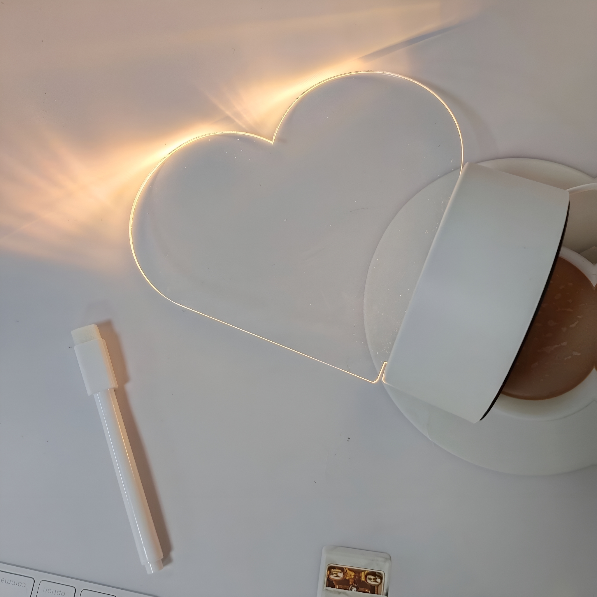 Ein herzförmiges Licht über einer Teetasse auf einer Untertasse, mit Stift und Aufklebern.