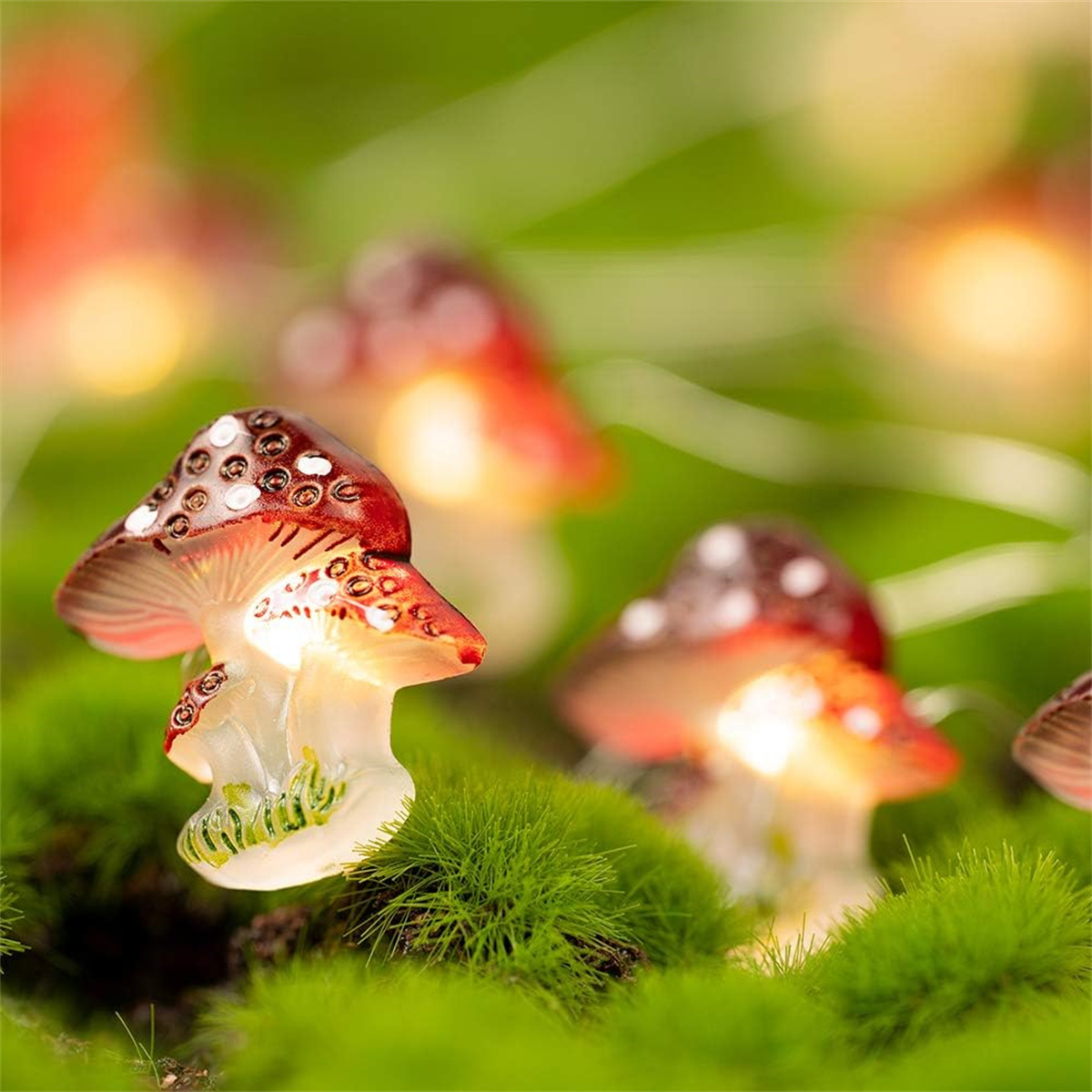 Nahaufnahme von beleuchteten Pilz-Lichterketten, auf grünem Moos platziert.