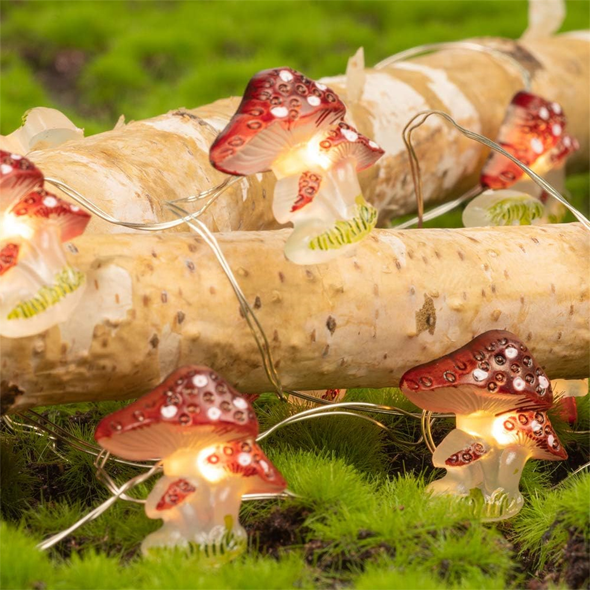 Lichterkette mit roten pilzförmigen Lichtern auf einem Holzstamm und grünem Moos.