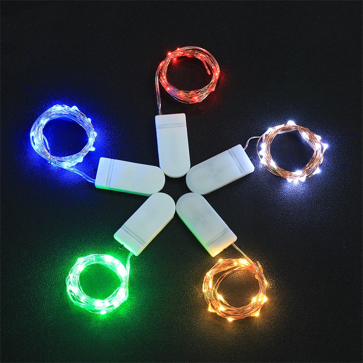 Bunte LED-Lichterketten in kreisförmiger Anordnung mit Batterien auf schwarzem Hintergrund.