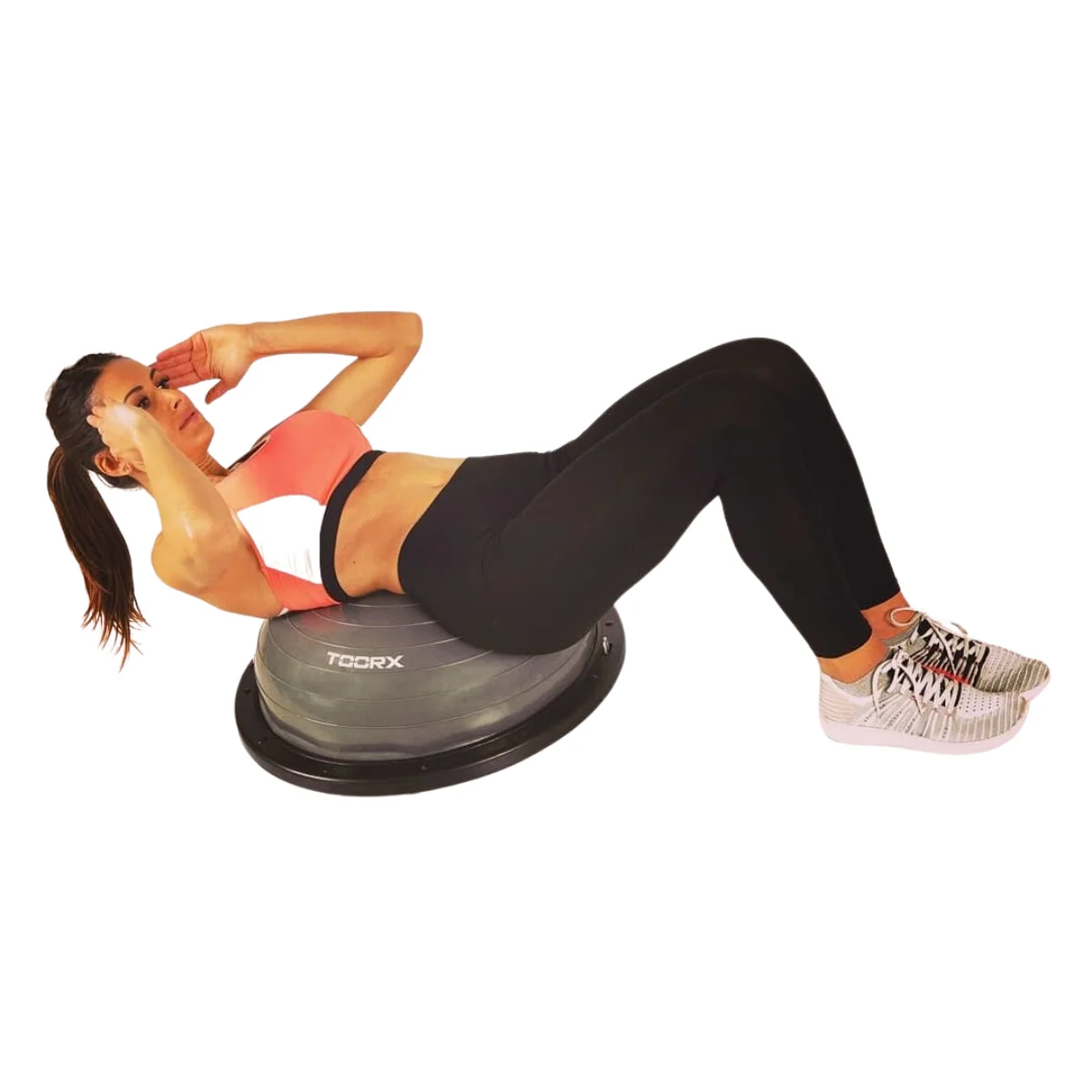 Femme faisant des redressements assis sur une planche d'équilibre. Elle porte des vêtements d'entraînement et est dans une salle de sport.