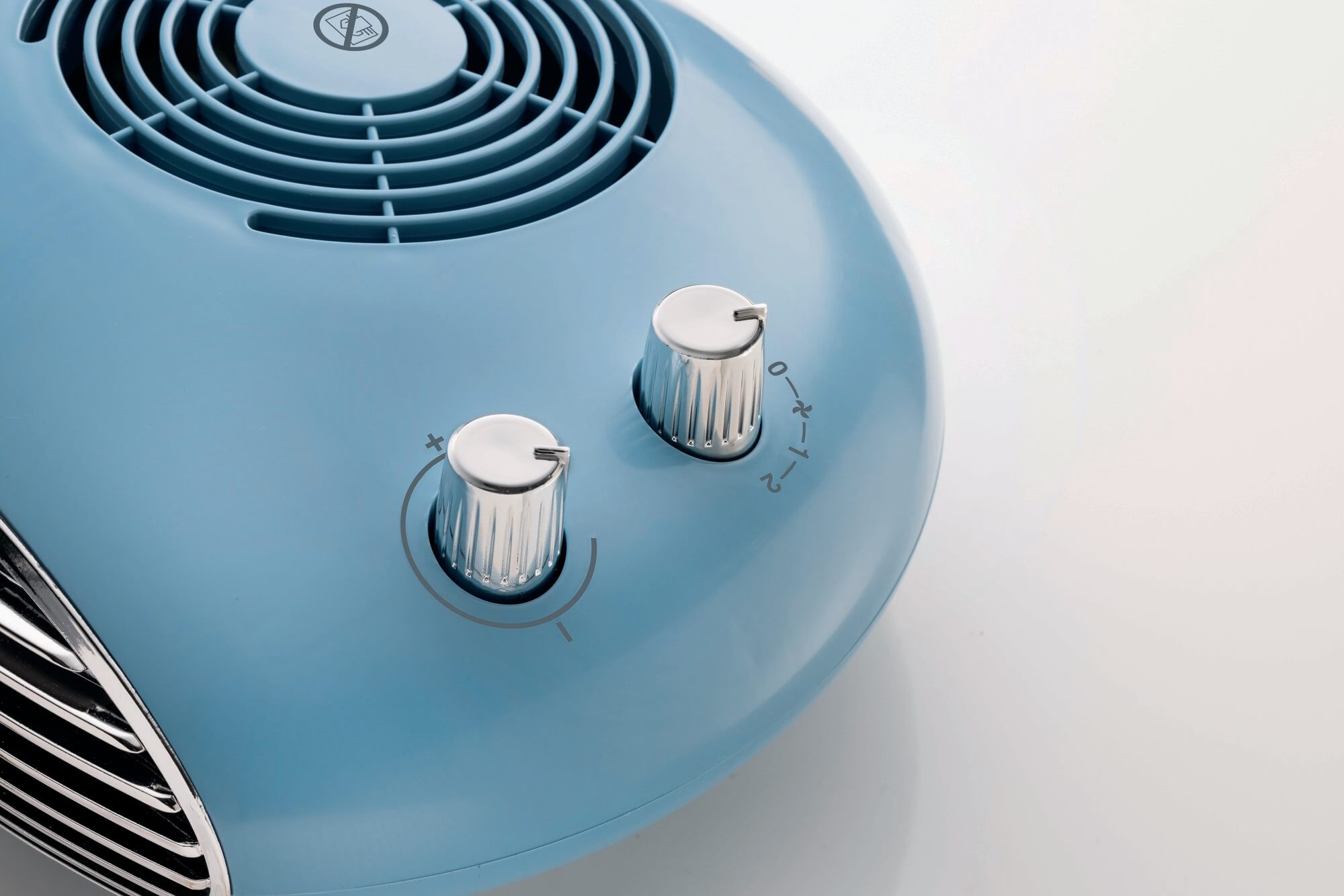 Een blauwe retro-ventilatorverwarmer met twee chromen bedieningsknoppen.