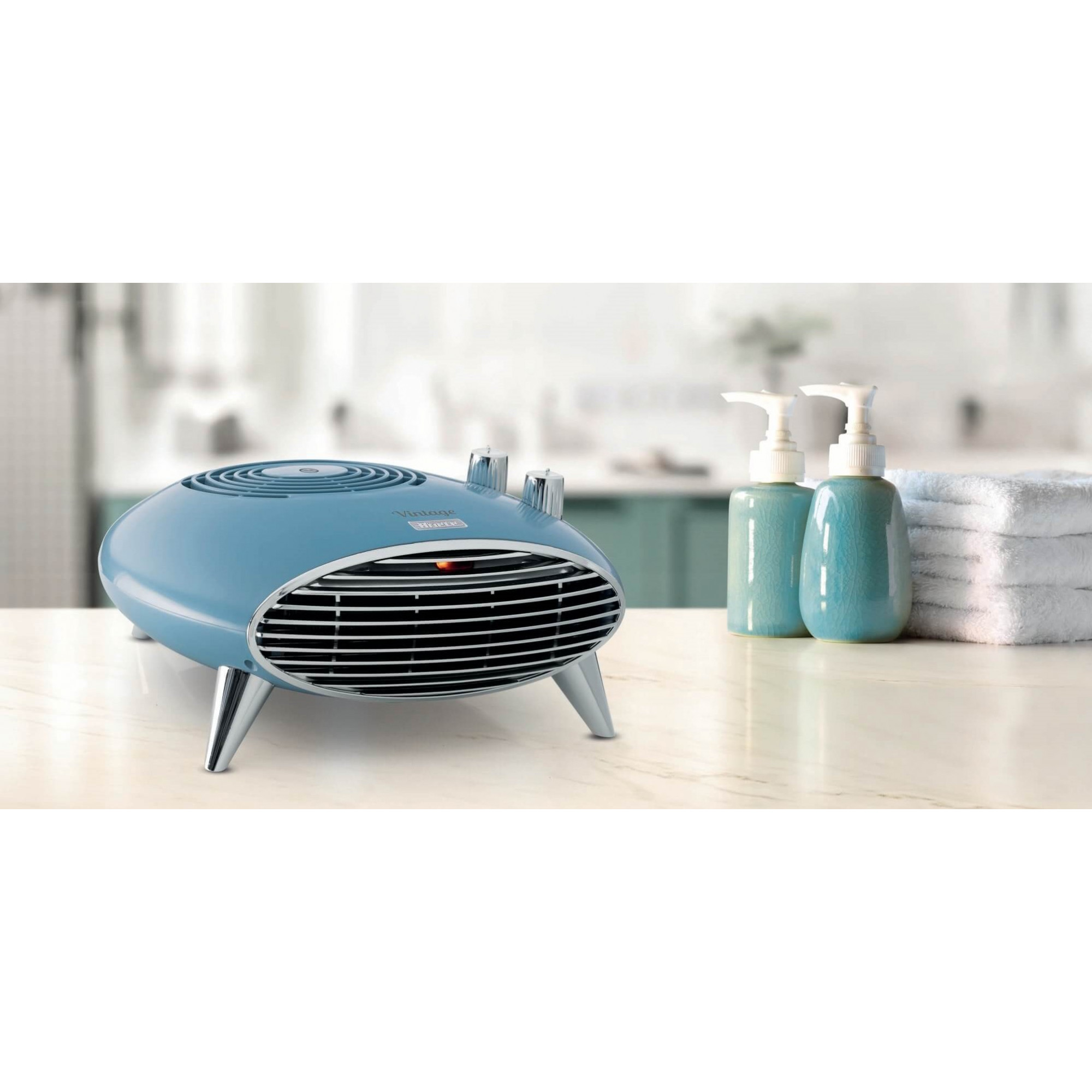 Blauwe retro elektrische kachel met chromen poten en een chromen grill. Twee teal flessen rechts.