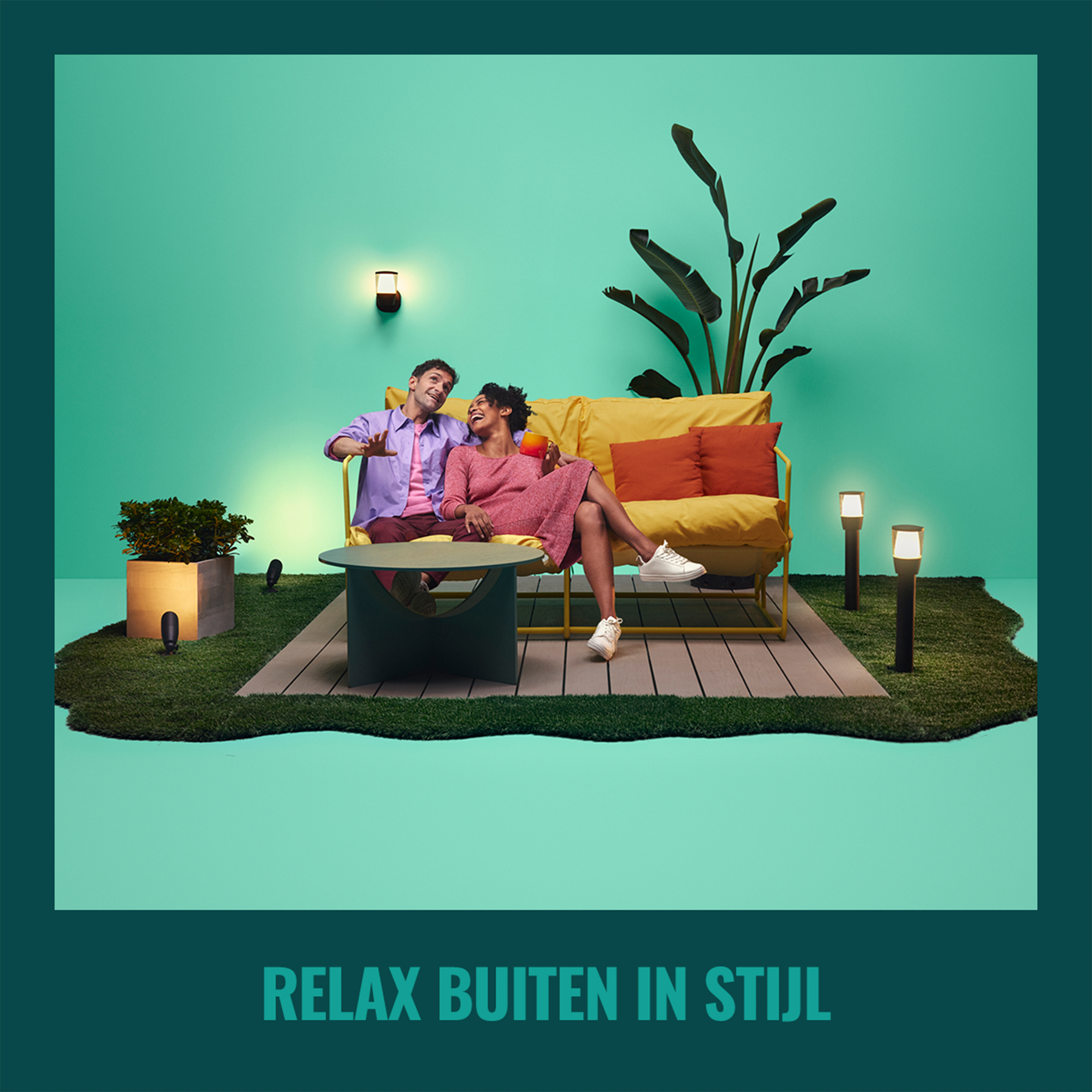 A couple on yellow couch with a table in front of them, teal background.