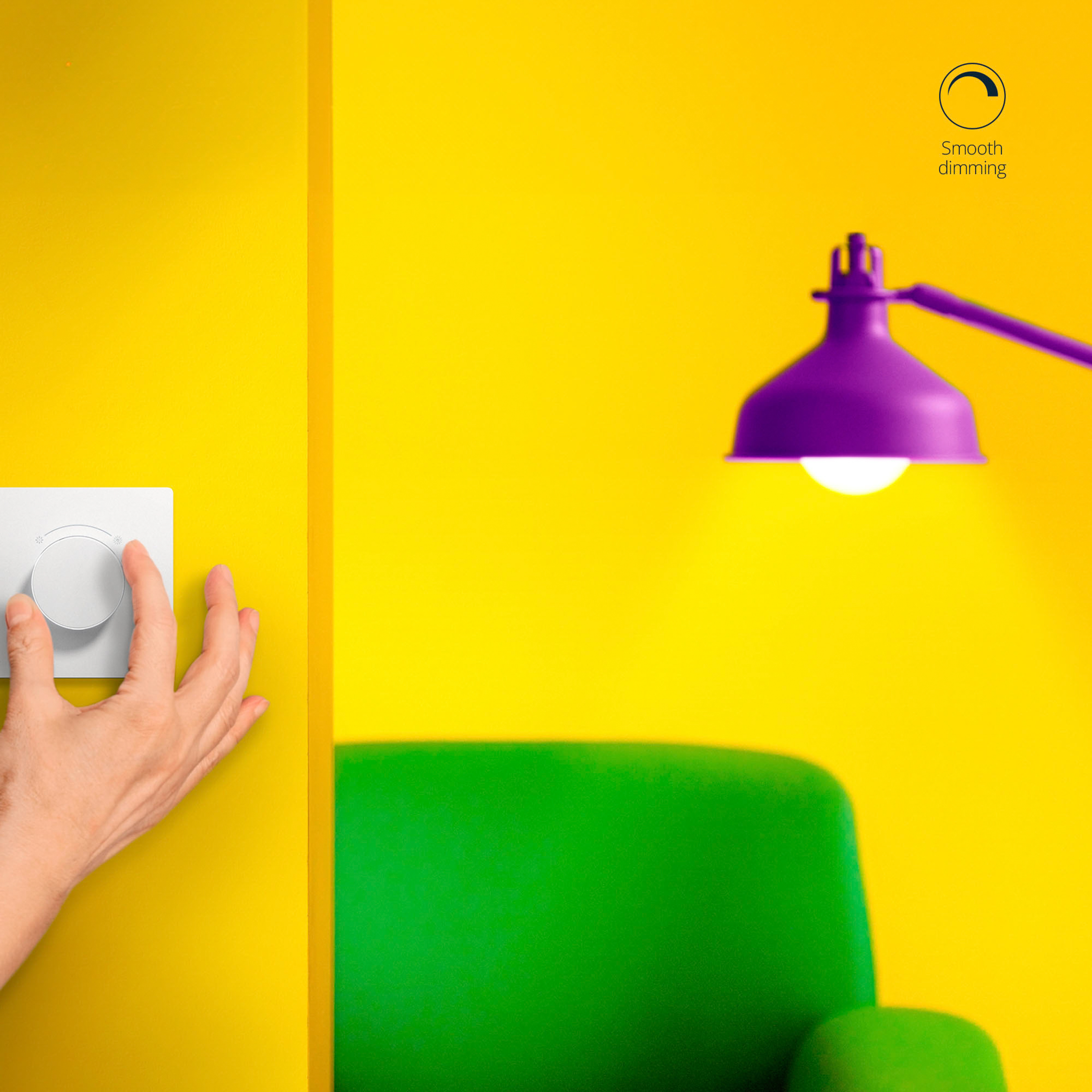 Een hand draait aan een draaiknop op een wit apparaat naast een gele muur, met een groene stoel en lamp.