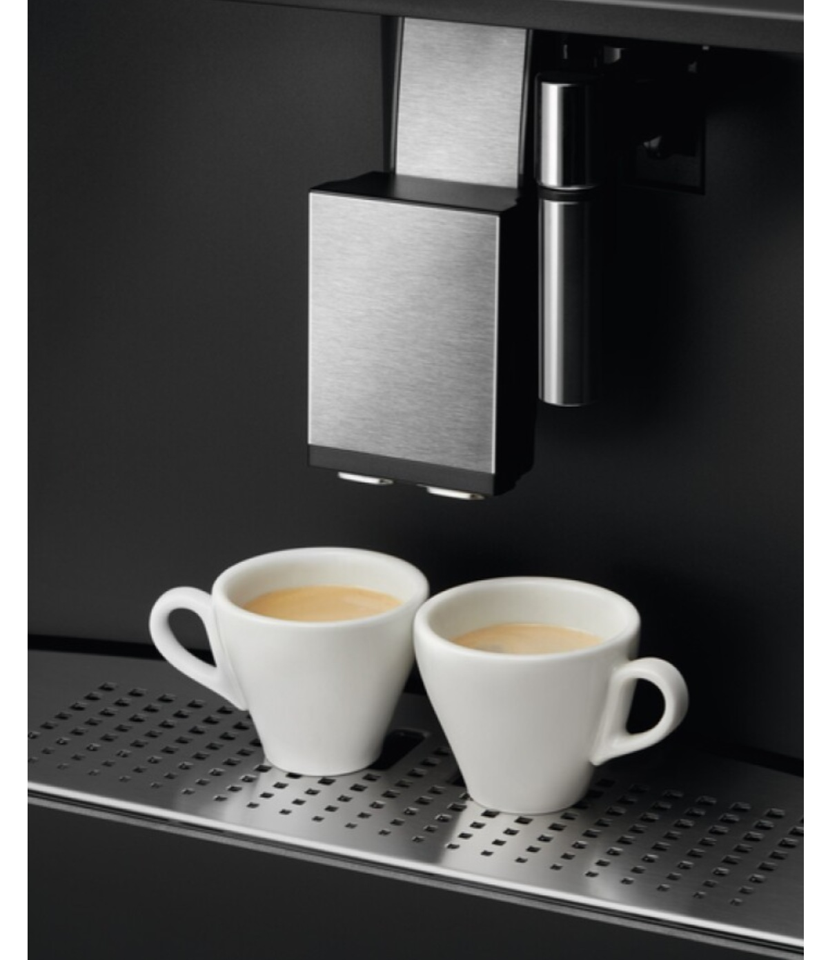Cafetera con dos tazas blancas llenas de café. El fondo es negro.