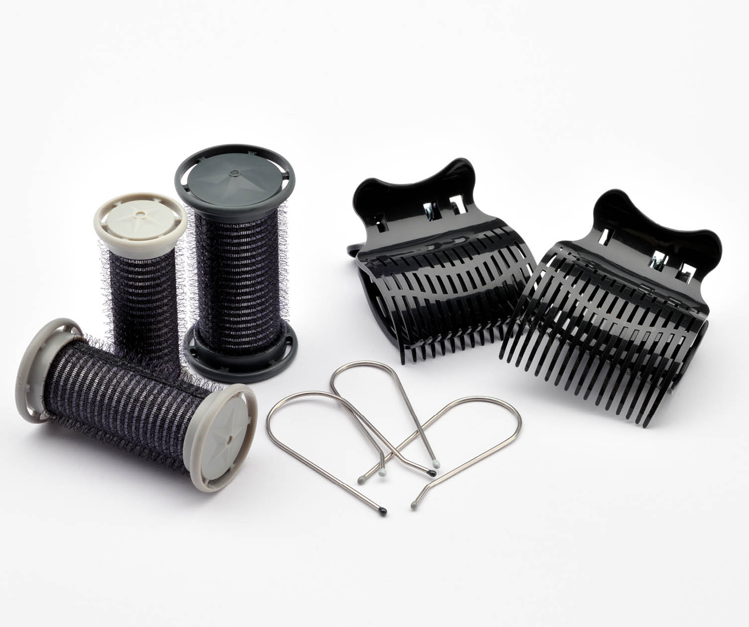 Hair rollers and clips on white background. Black clips and silver pins. Gray and black rollers.