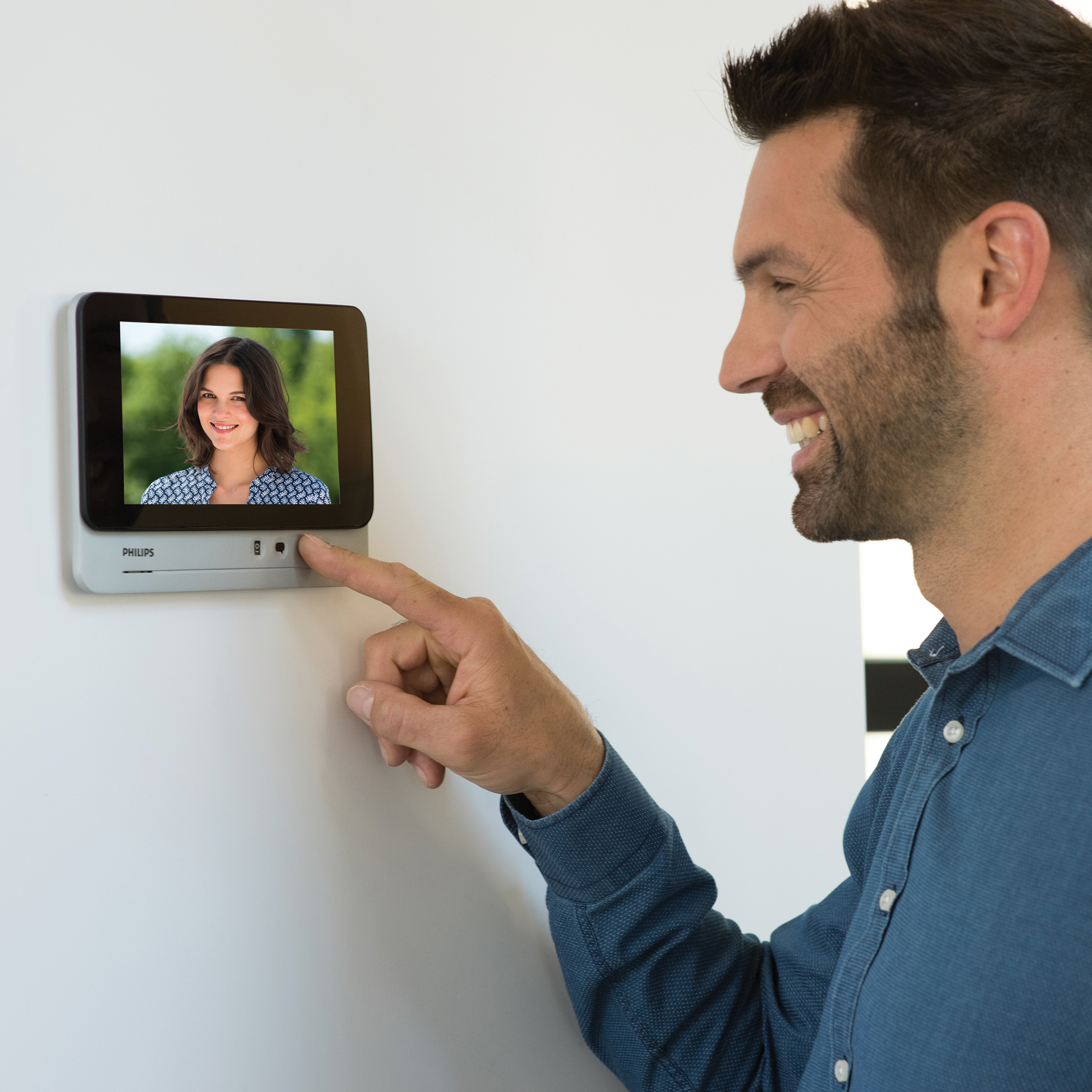 Un hombre señalando una pantalla inteligente con imagen de mujer. Intercomunicador.
