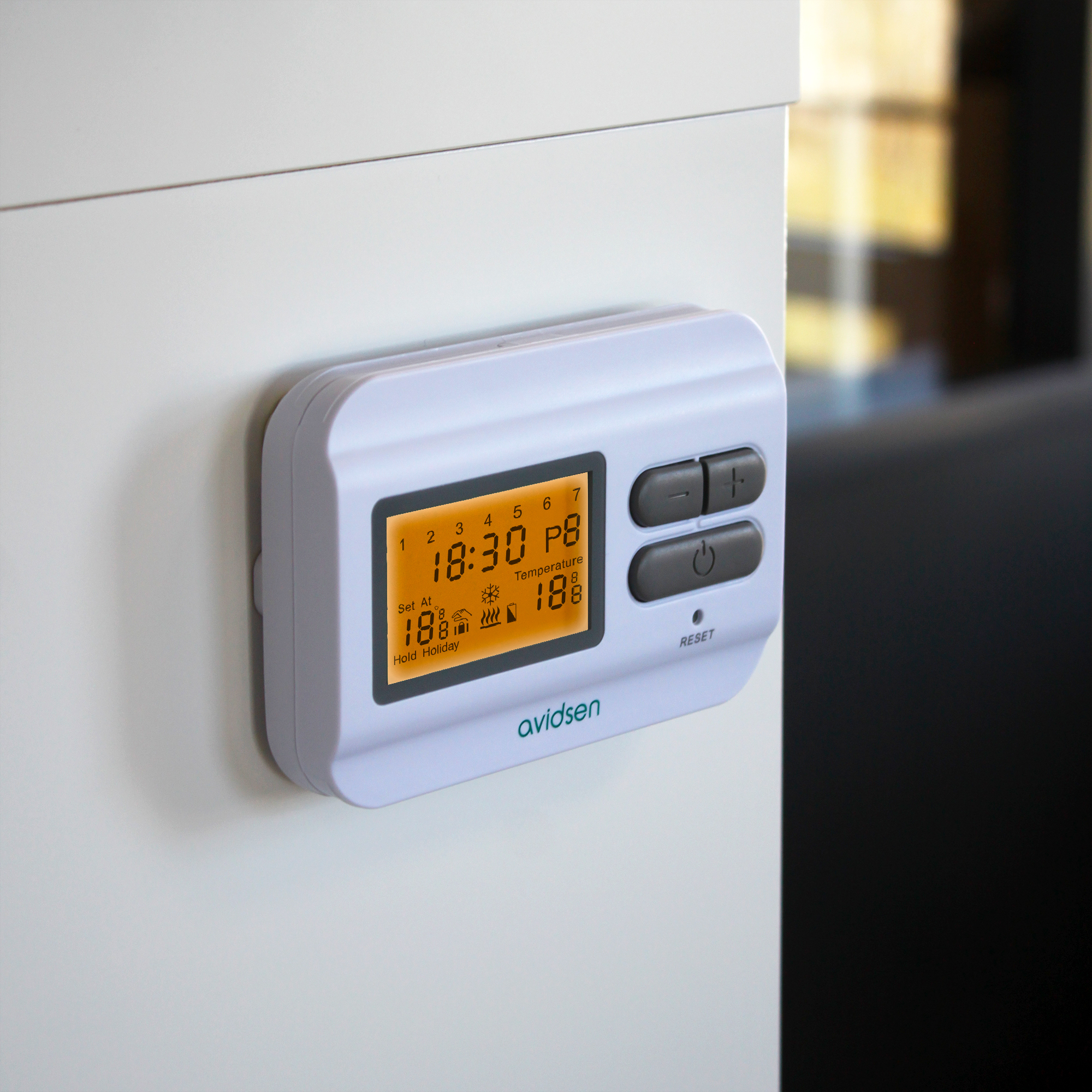 Termostato bianco a parete. Il display mostra ora, temperatura e impostazioni. Pulsanti grigi.