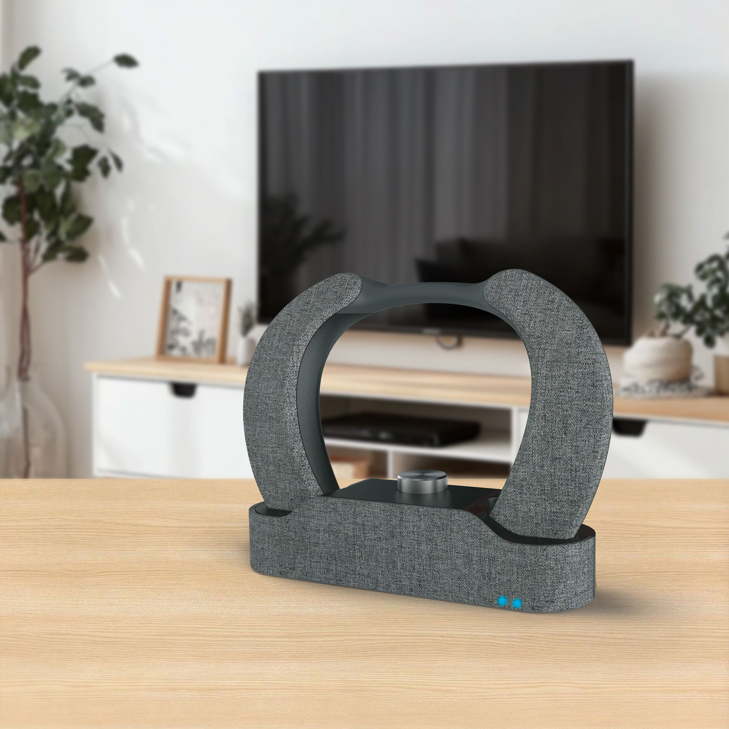 Eine graue Soundbar auf einem Holztisch vor einem Fernseher. Der Hintergrund umfasst einen weißen Schrank und ein Fenster.