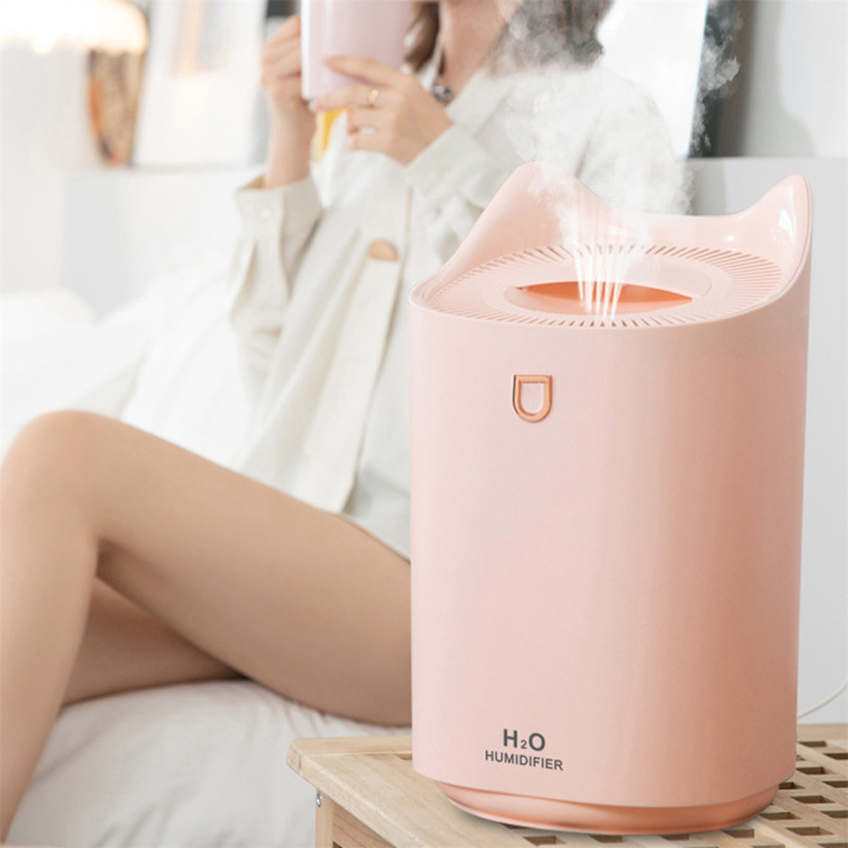 Ein rosa Luftbefeuchter mit einzigartigem Top-Design, der Dampf abgibt, neben einer Person.