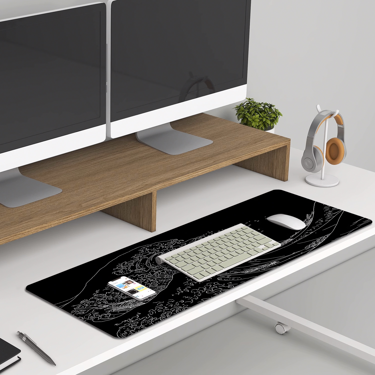 Konfiguracja biurka: podwójne monitory, klawiatura, mysz, telefon, słuchawki i roślina na białym biurku.