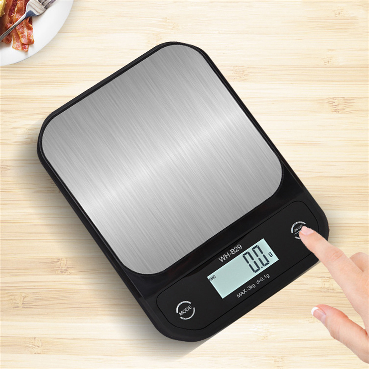 Schwarze und silberne digitale Küchenwaage, der Finger einer Person berührt die Ein-Taste.