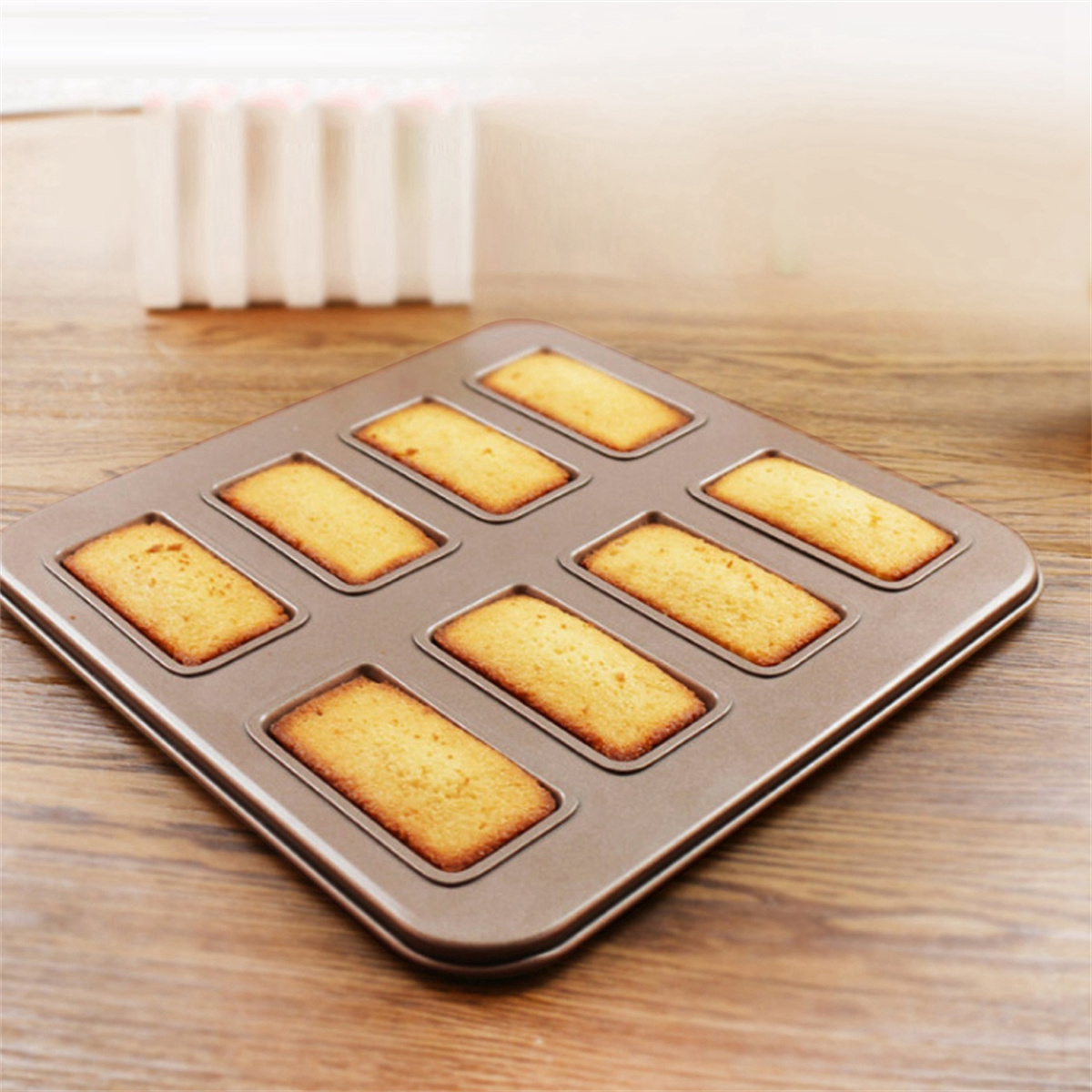 Eine Backform enthält acht rechteckige Kuchen. Die Kuchen sind goldbraun, die Form dunkelbraun.