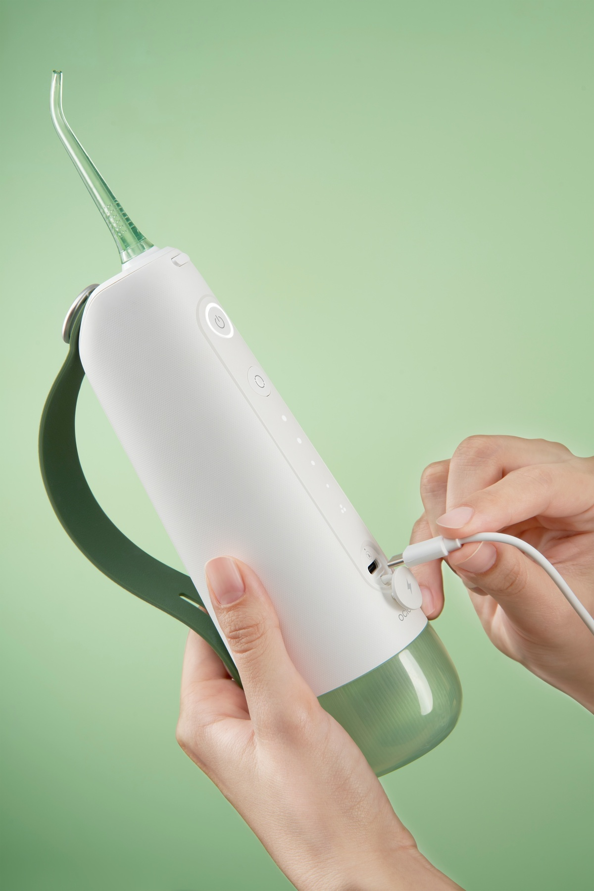 Ein weiß-grüner Munddusche, in die eine Hand ein Ladekabel steckt.