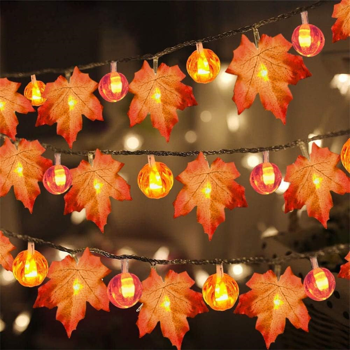 Lichterkette mit orangefarbenen Ahornblatt- und kürbisförmigen Lichtern. Sie hängen über dem Rahmen.