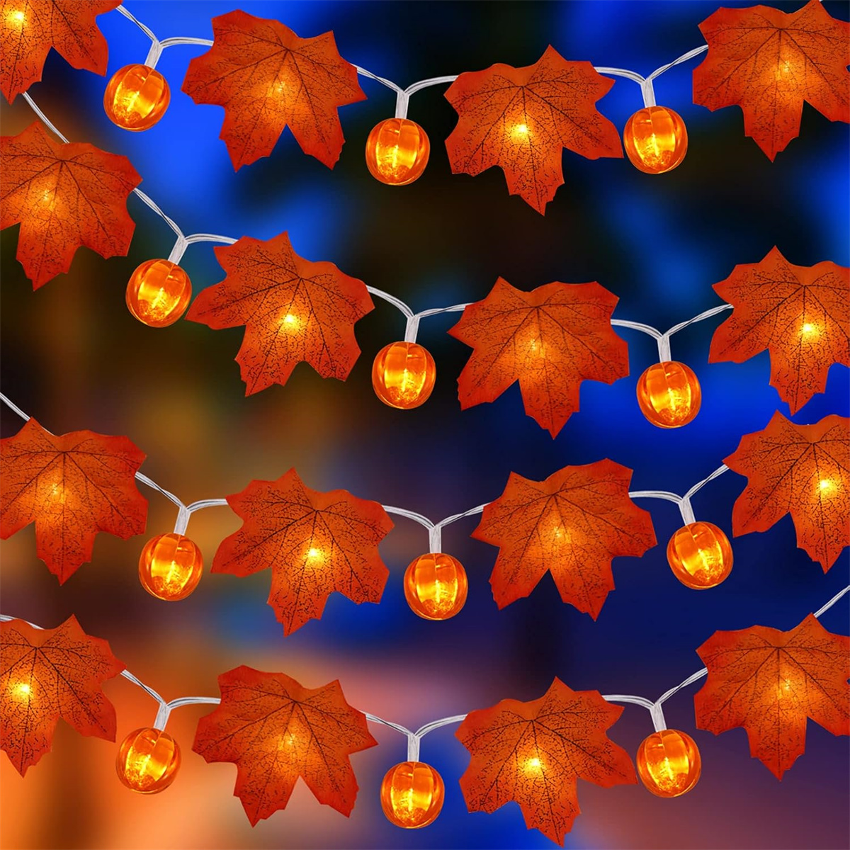 Lichterketten mit Ahornblatt- und Kürbisdekorationen, vor verschwommenem blau-orangem Hintergrund.