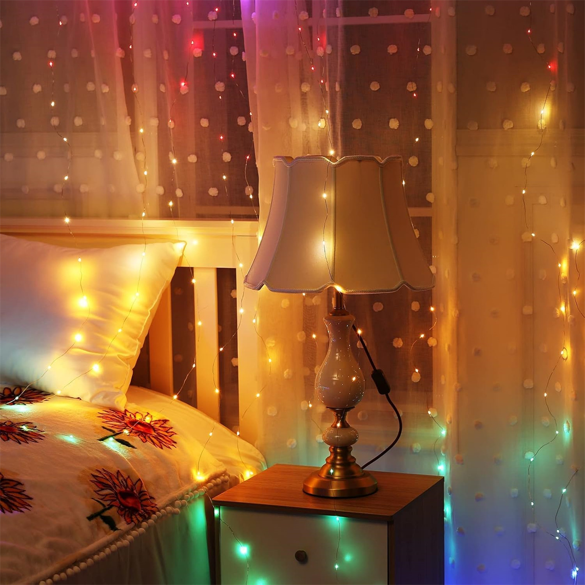 Ein Schlafzimmer bei Nacht mit Lampe, Lichterketten, Bett und Vorhängen.