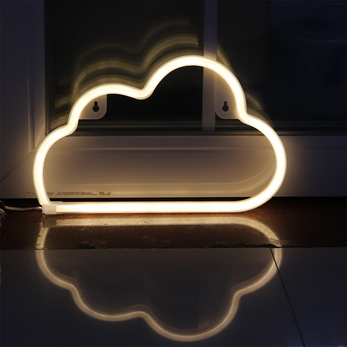 Eine wolkenförmige Neonleuchte, mit warmem Schein, spiegelt sich auf einer glänzenden Oberfläche vor dunklem Hintergrund.