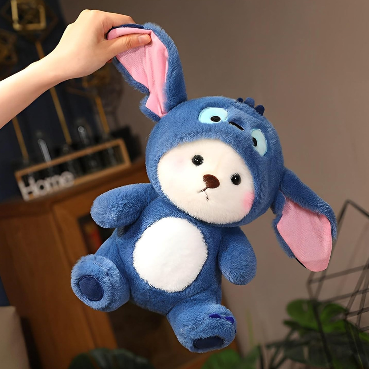 Blaues Spielzeug-Häschen mit weißem Bauch und rosa Ohren. Person hält das Spielzeug.