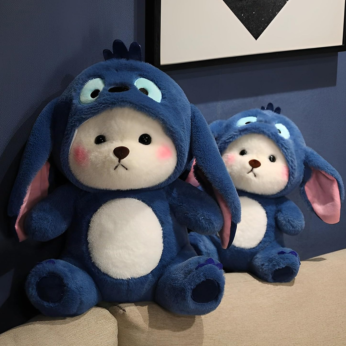 Zwei blaue Plüschtiere, die Stitch ähneln, mit großen Köpfen und Ohren, auf blauem Hintergrund.