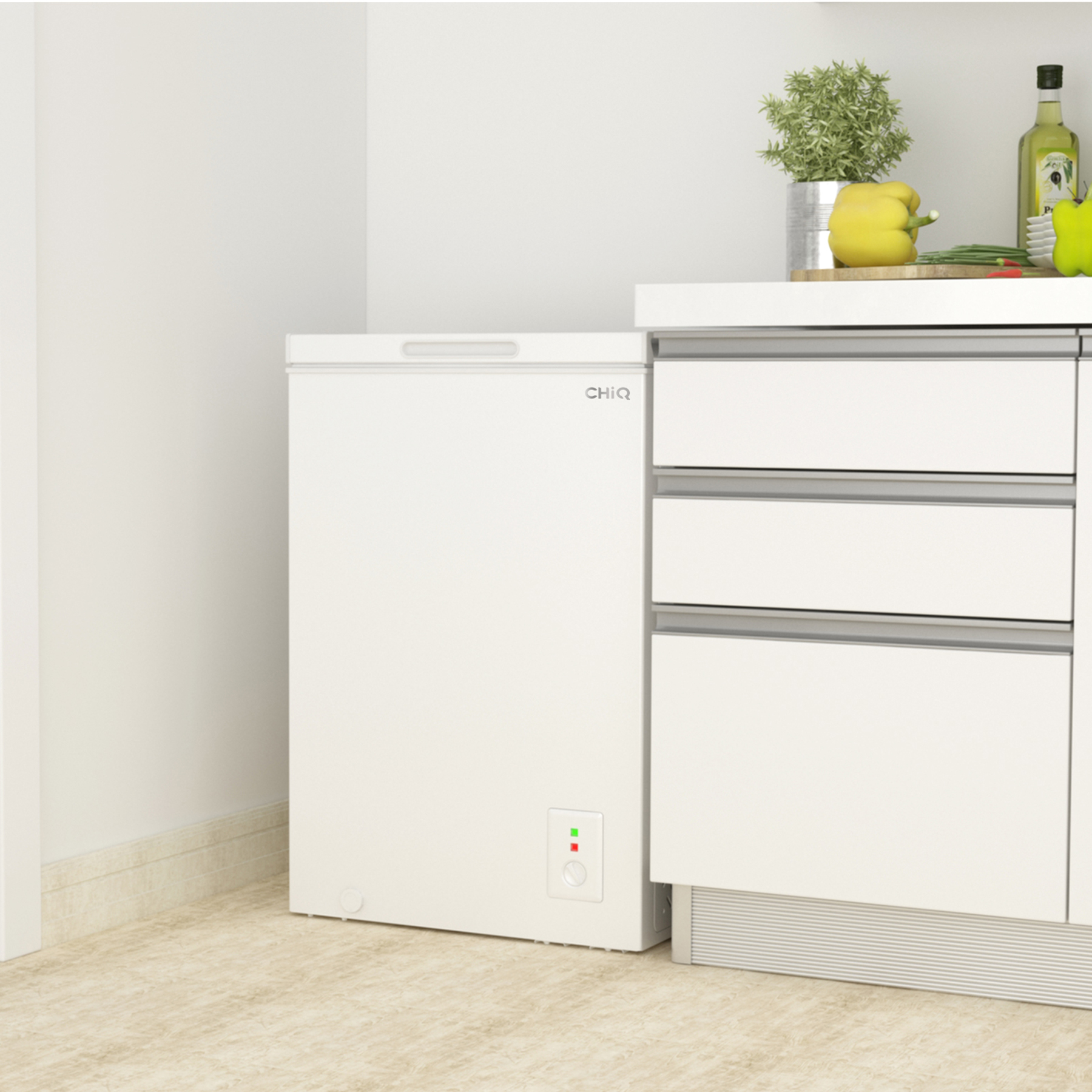 Weiße Truhen-Gefriertruhe neben einem weißen Schrank in einer Küche mit Pflanzen und Essen.