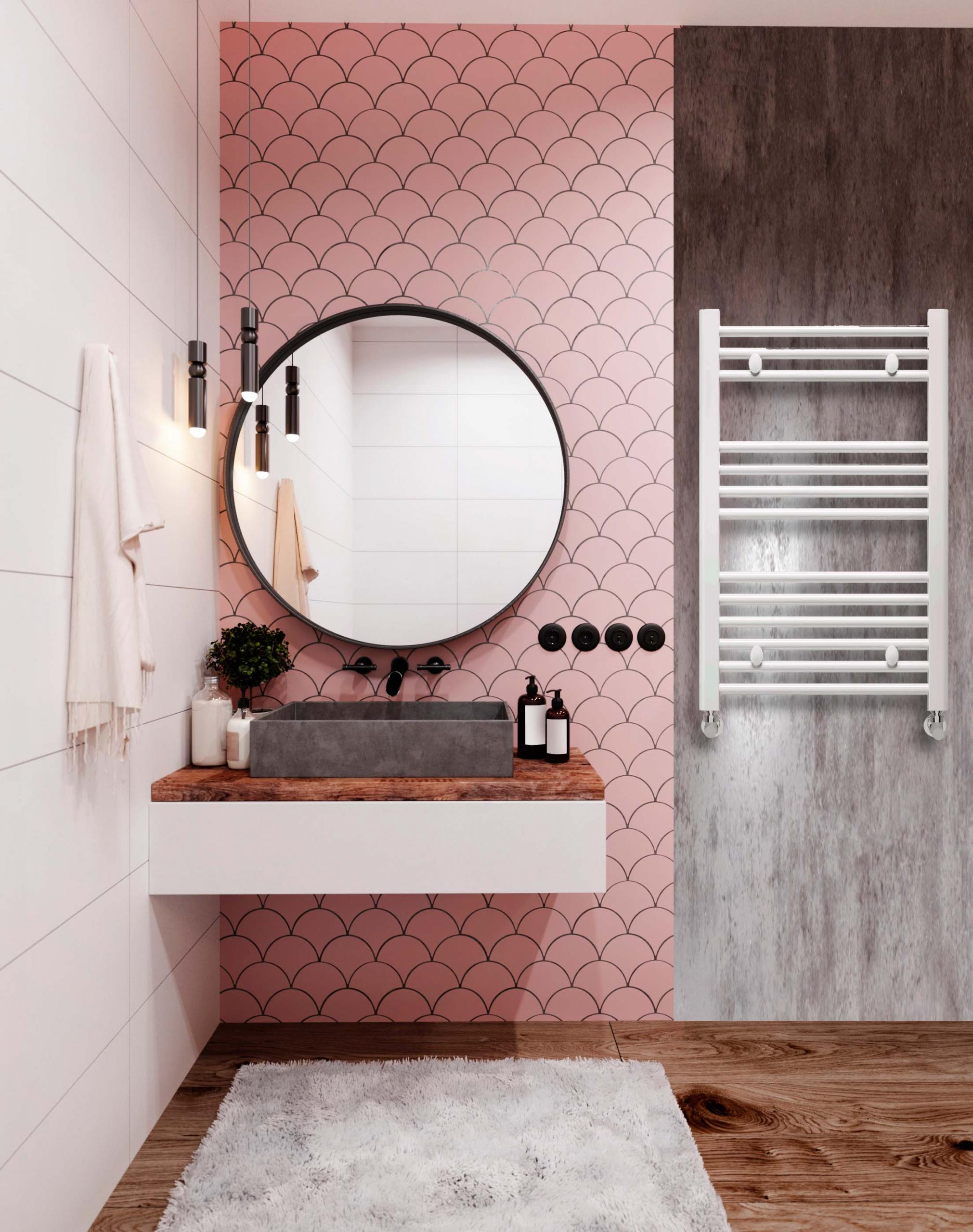 Un baño con una pared de azulejos rosas, un espejo redondo y una toalla blanca.