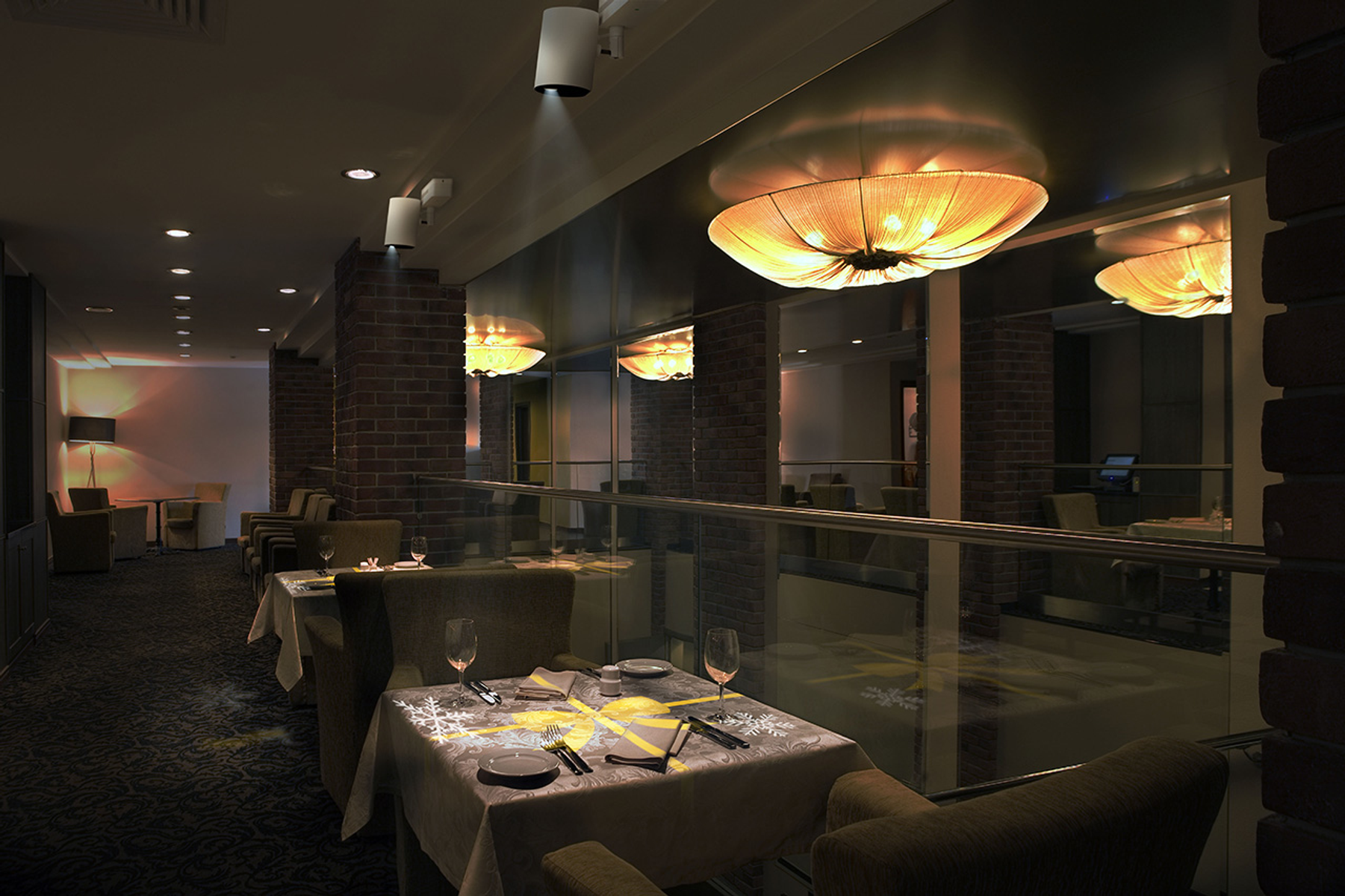Un interno di ristorante tenue con tavoli, sedie e illuminazione decorativa.