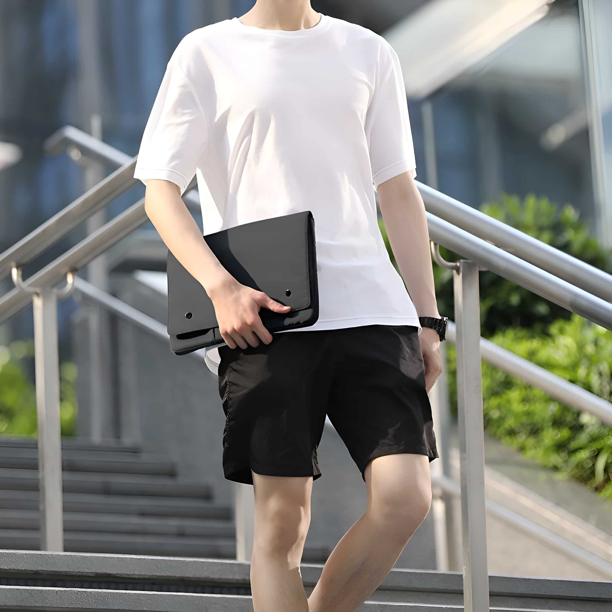 Ein Mann in weißem T-Shirt und schwarzer Hose geht eine Treppe hinunter und hält eine schwarze Tasche.