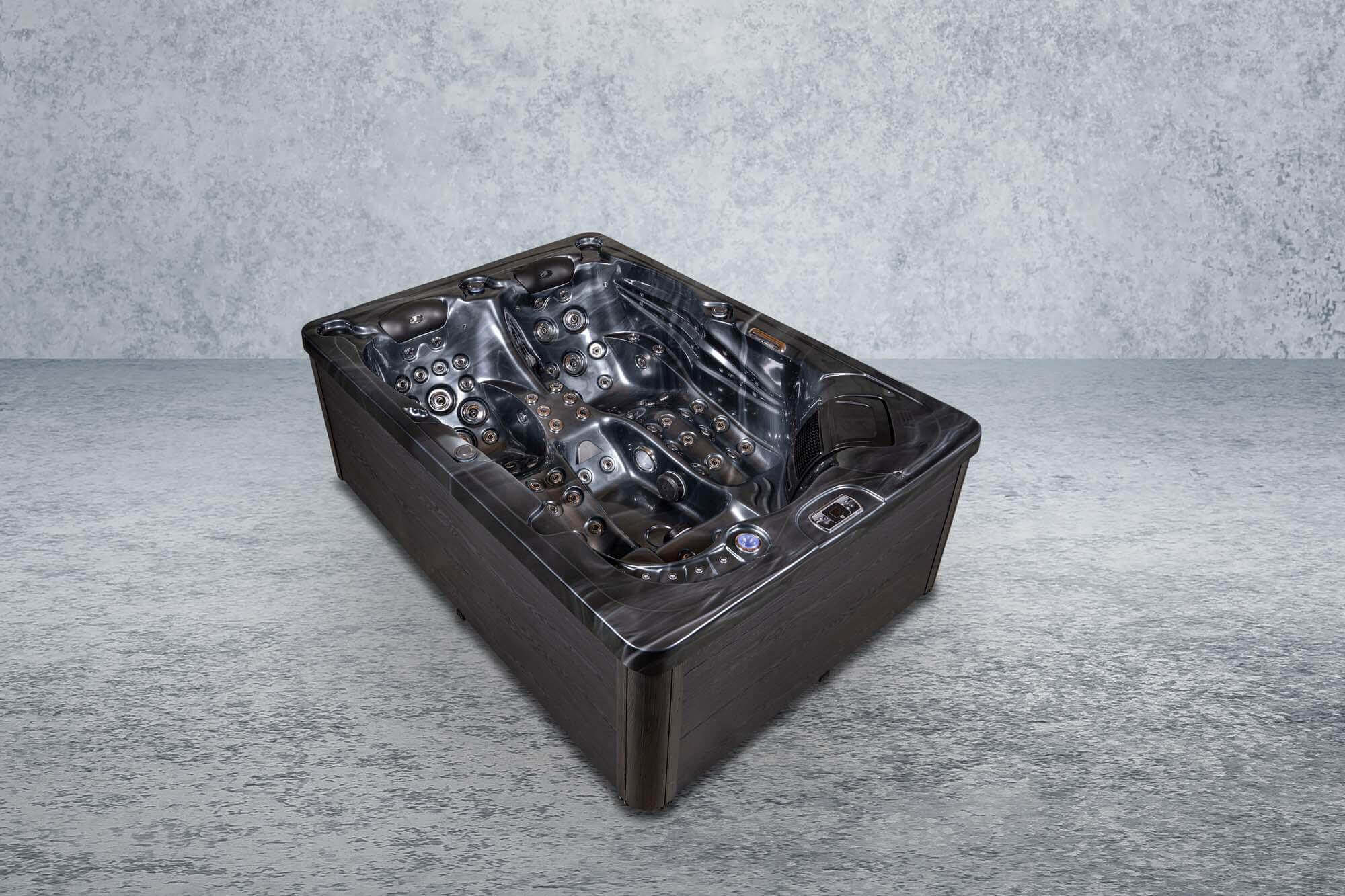 Ein dunkel gefärbter Whirlpool steht auf einer grauen Betonoberfläche mit neutralgrauem Hintergrund.