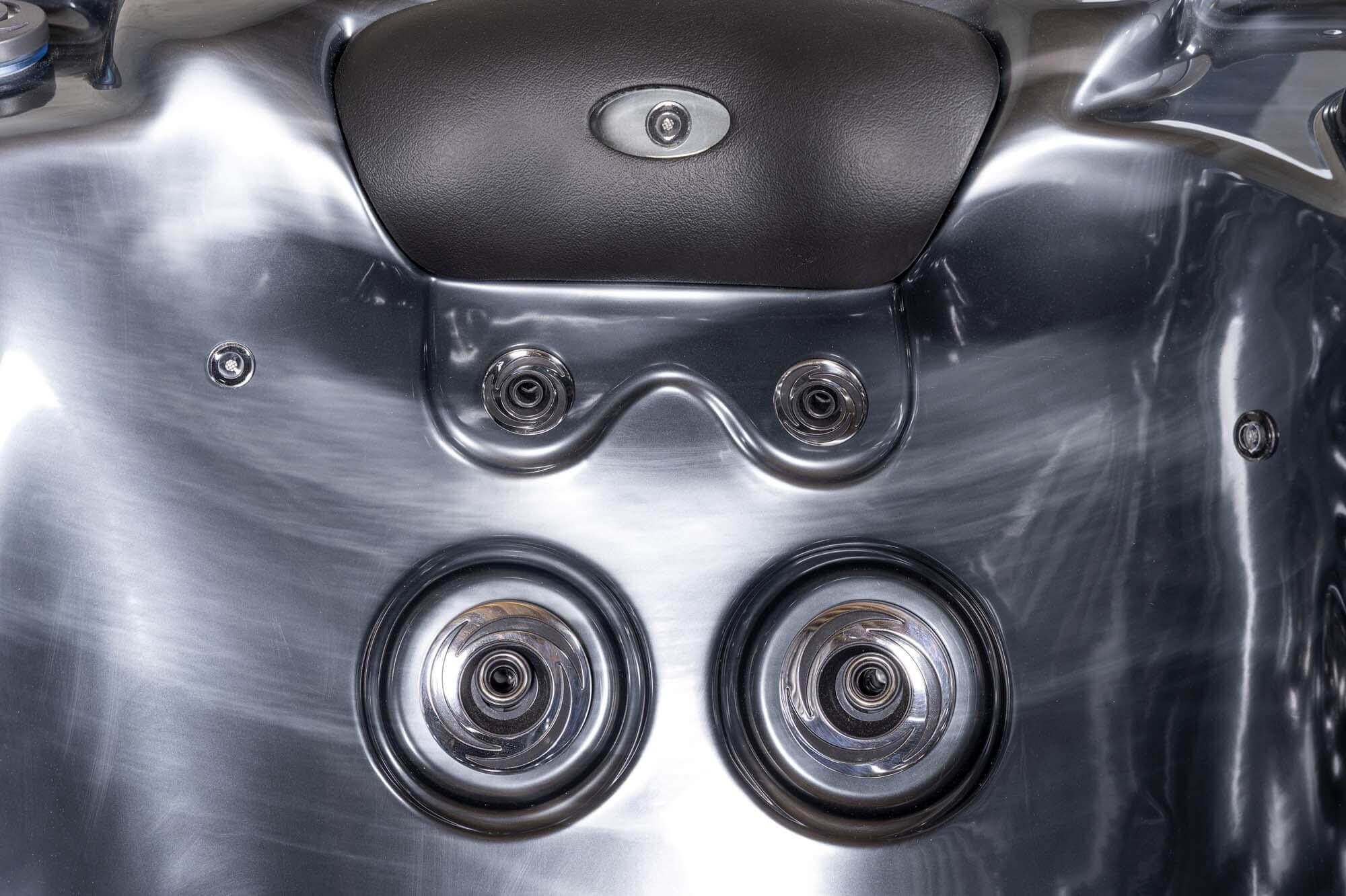 Nahaufnahme eines glänzenden, metallischen Whirlpool-Innenraums mit Düsen und Bedienfeld.