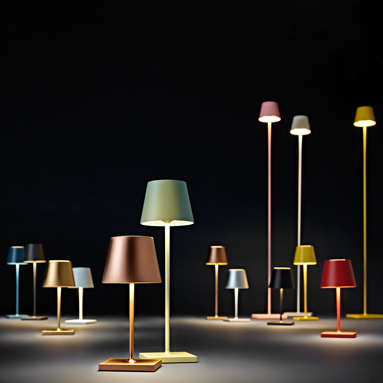 Eine Vielzahl von bunten Lampen, einige auf Ständern, einige auf Tischen, alle mit beleuchteten Lampenschirmen.
